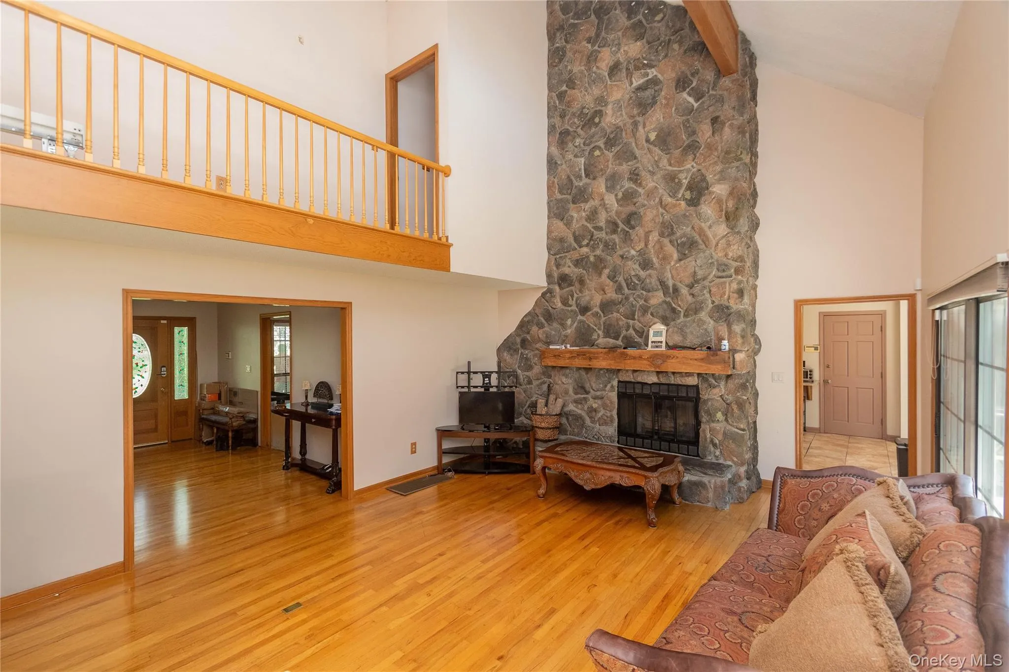 Living room featuring light wood finished floors, a fireplace, and vaulted ceiling Living room featuring light wood finished floors, a fireplace, and vaulted ceiling