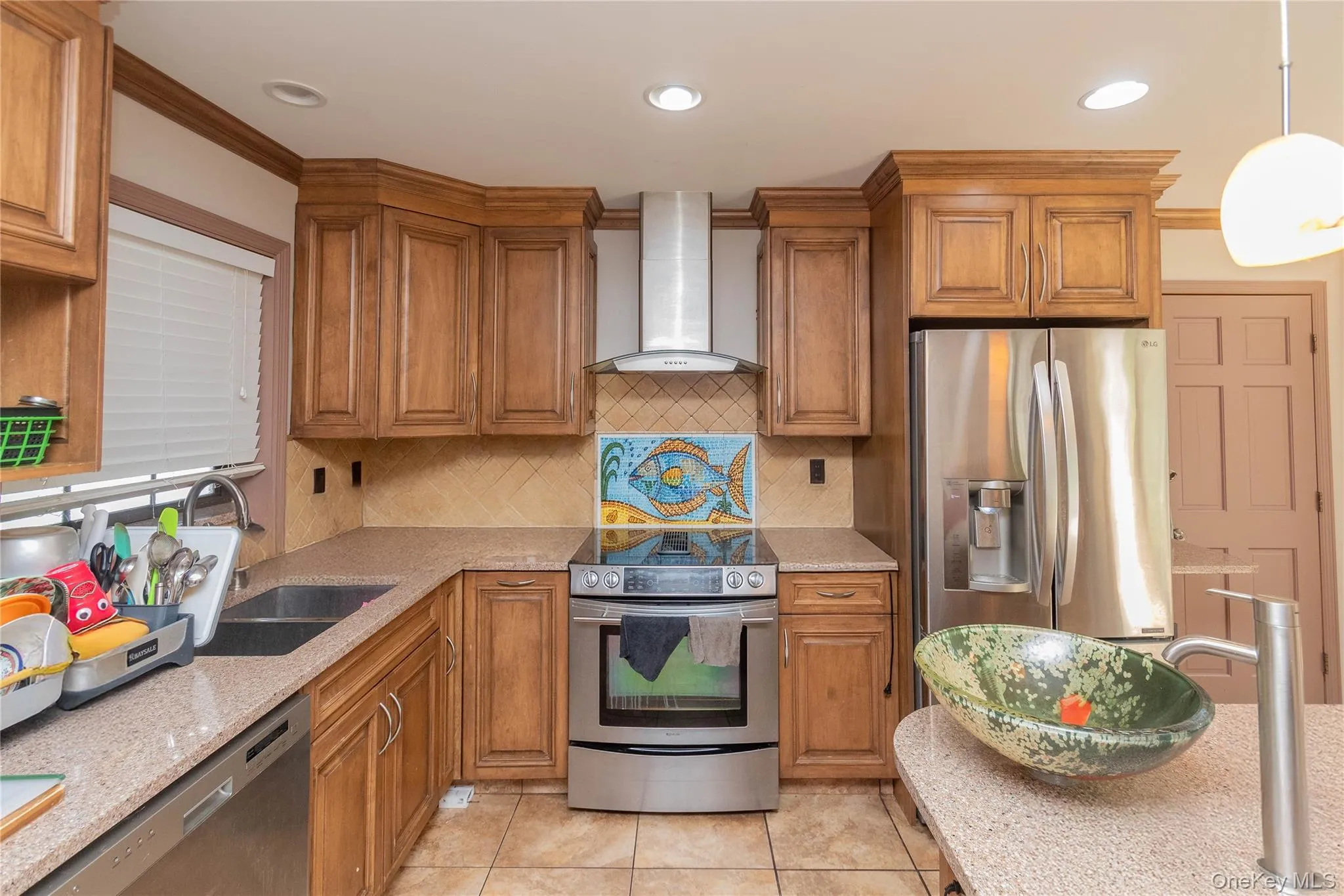 Kitchen with wood finish cabinetry, stainless steel appliances, light tile patterned flooring, and granite counters Kitchen with wood finish cabinetry, stainless steel appliances, light tile patterned flooring, and granite counters