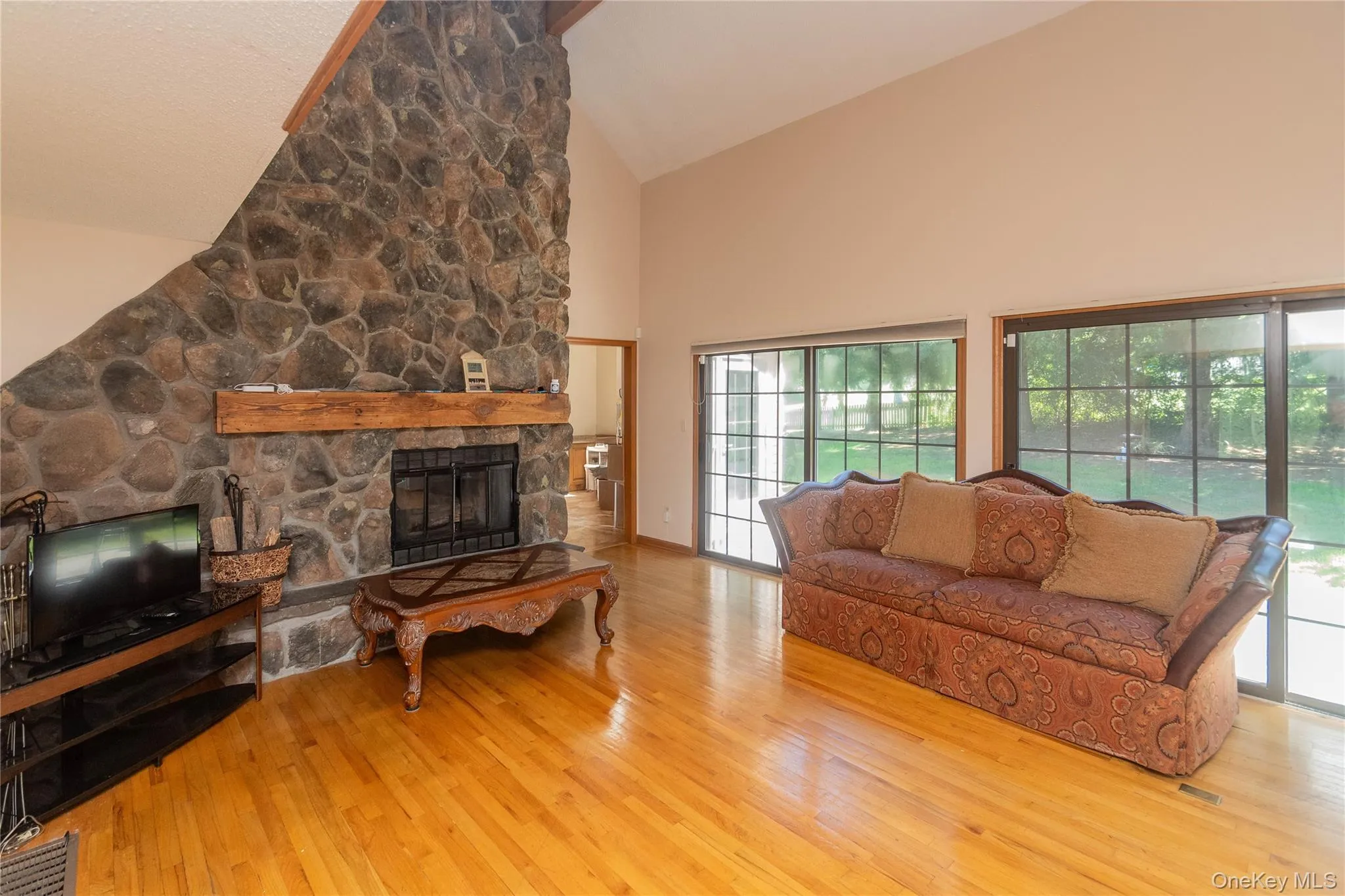 Living room with vaulted ceiling, light wood finished floors, and a fireplace Living room with vaulted ceiling, light wood finished floors, and a fireplace
