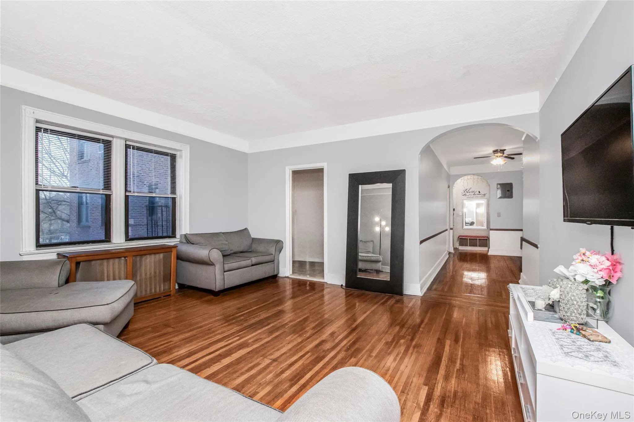 Living room with wood finished floors, arched walkways, and a ceiling fan Living room with wood finished floors, arched walkways, and a ceiling fan