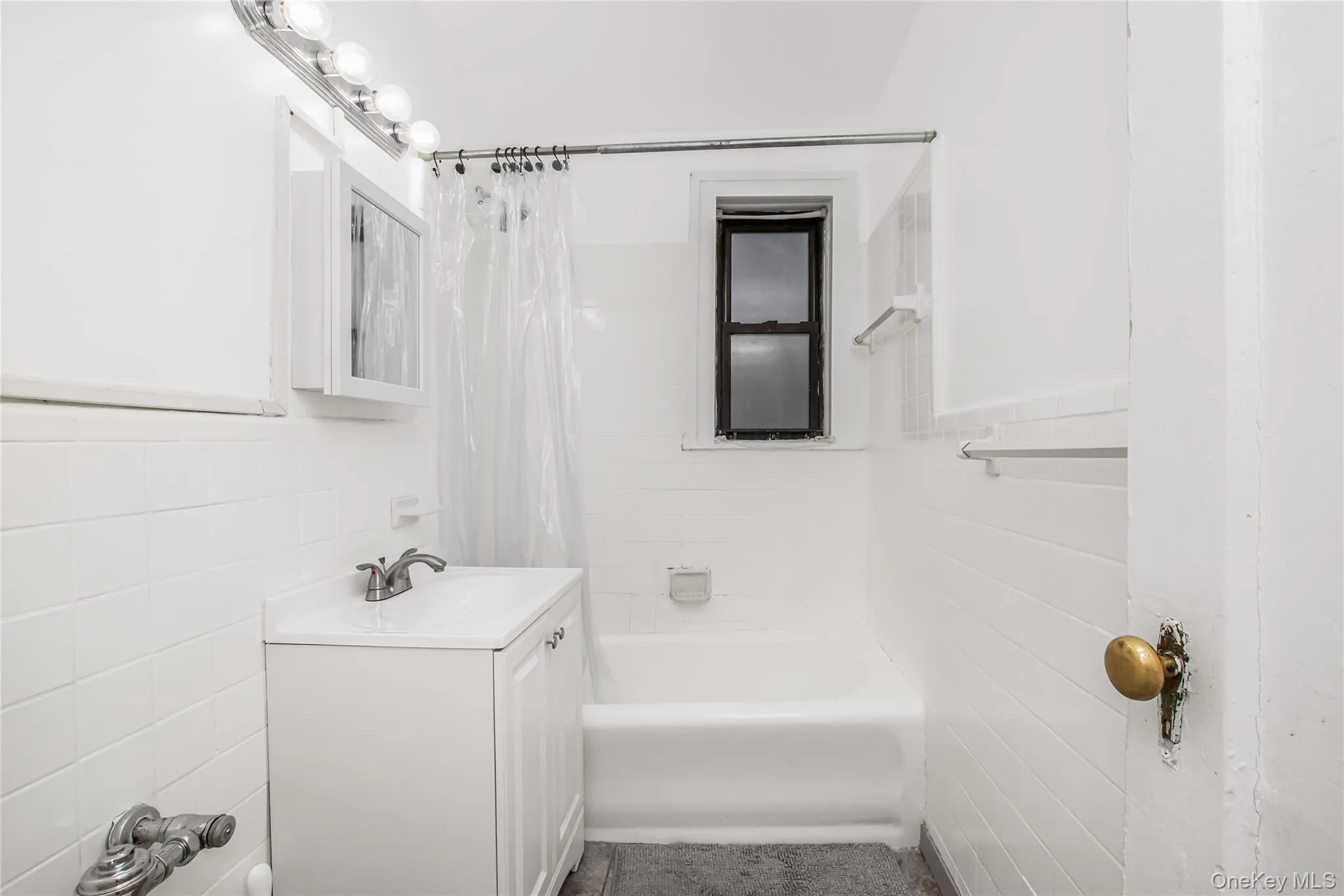 Full bathroom with tile walls, shower / tub combo, vanity, and a wainscoted wall Full bathroom with tile walls, shower / tub combo, vanity, and a wainscoted wall