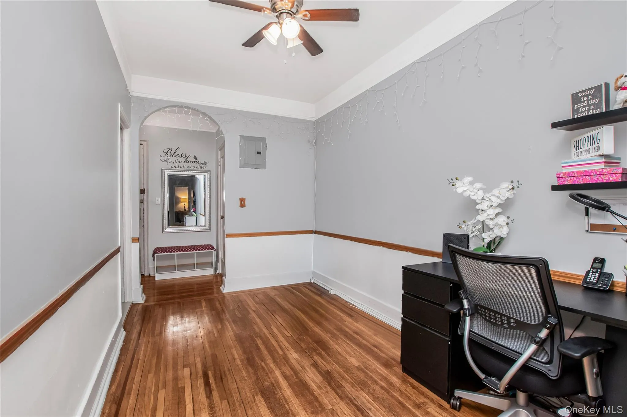 Unfurnished office with dark wood-style flooring, arched walkways, ceiling fan, and electric panel Unfurnished office with dark wood-style flooring, arched walkways, ceiling fan, and electric panel