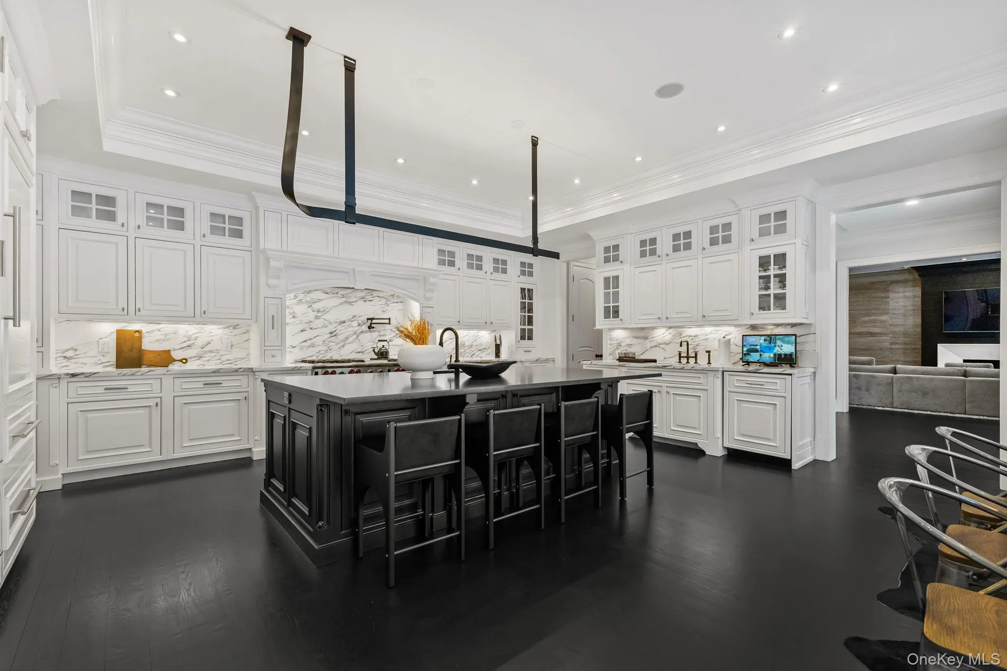 Custom wood cabinetry is beautifully complemented by glass-front upper cabinets for display, while exquisite book-matched Arabescato marble crowns the countertops and backsplash. Undercabinet lighting enhances the ambiance, and a secondary sink provides additional, thoughtfully designed workspace. Custom wood cabinetry is beautifully complemented by glass-front upper cabinets for display, while exquisite book-matched Arabescato marble crowns the countertops and backsplash. Undercabinet lighting enhances the ambiance, and a secondary sink provides additional, thoughtfully designed workspace.