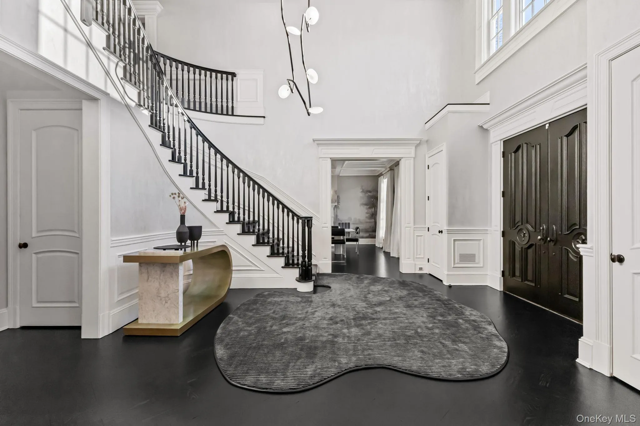 A grand two-story entrance showcases a custom coffered ceiling with recessed lighting and Motorized Chandelier Lift System, elaborate wainscoting throughout, and a sweeping staircase that truly takes your breath away. A grand two-story entrance showcases a custom coffered ceiling with recessed lighting and Motorized Chandelier Lift System, elaborate wainscoting throughout, and a sweeping staircase that truly takes your breath away.