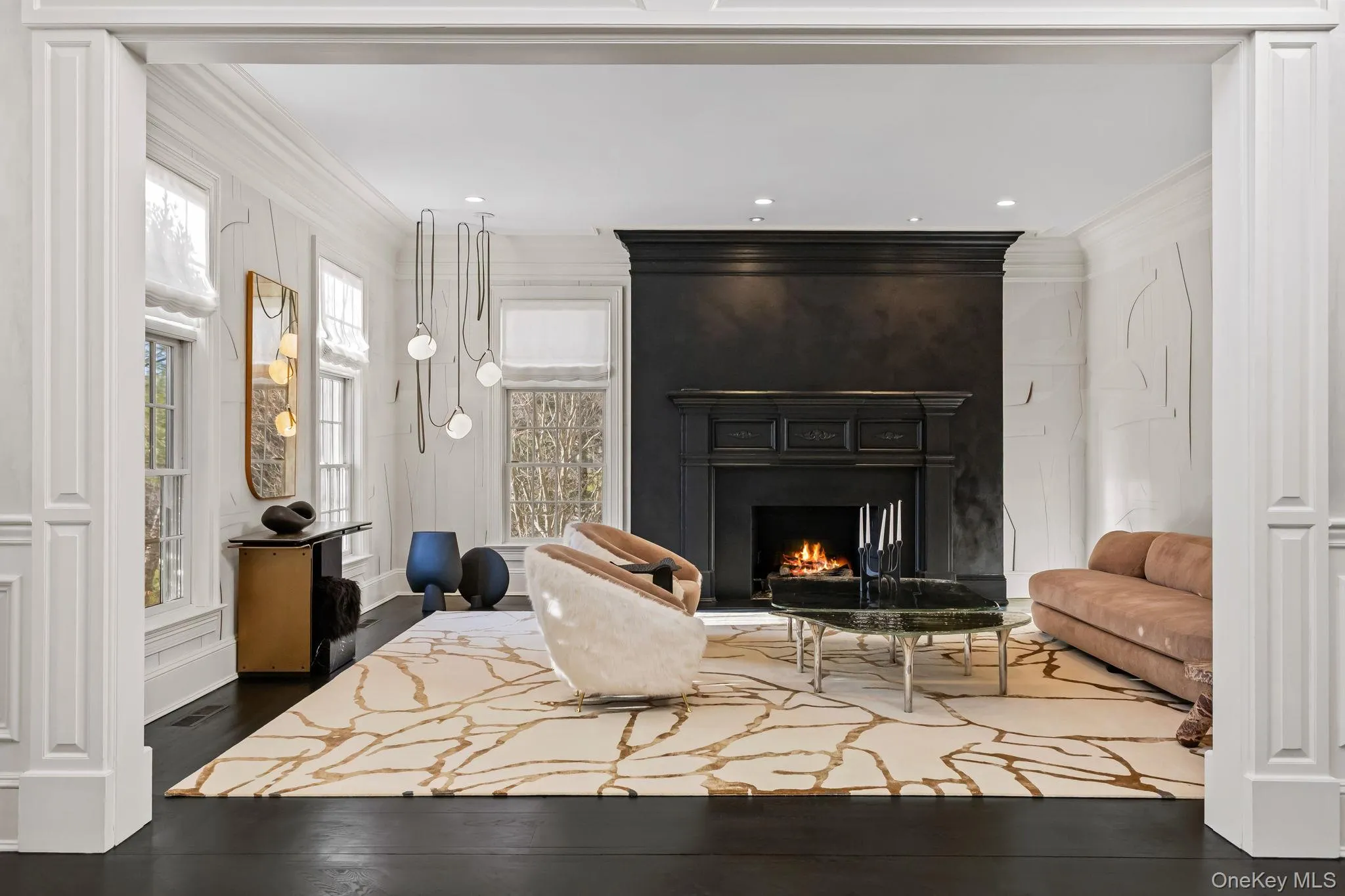 A custom-designed, wide-columned entry opens to a generously proportioned, light-filled Living Room highlighted by a striking masonry fireplace with a bespoke mantel and marble surround, complemented by in-ceiling speakers, designer custom lighting, and elegant wallpaper. A custom-designed, wide-columned entry opens to a generously proportioned, light-filled Living Room highlighted by a striking masonry fireplace with a bespoke mantel and marble surround, complemented by in-ceiling speakers, designer custom lighting, and elegant wallpaper.