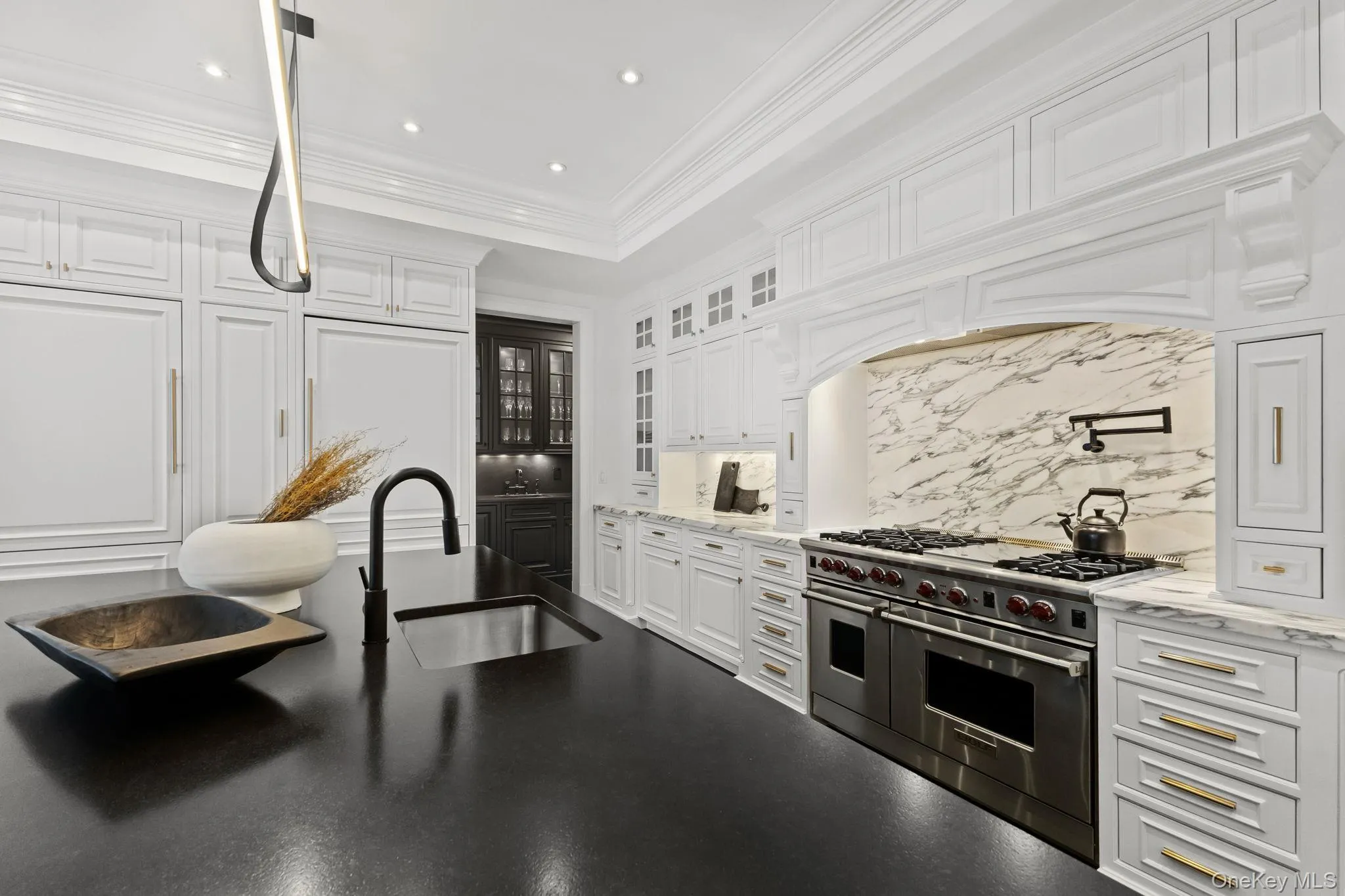 An outstanding Chef’s kitchen appointed with premium stainless steel appliances, including a Wolf six-burner range with griddle and convenient pot filler, two Sub-Zero refrigerators, a microwave, dual dishwashers, a warming drawer, and a professional-grade exhaust system, designed to meet every culinary demand. An outstanding Chef’s kitchen appointed with premium stainless steel appliances, including a Wolf six-burner range with griddle and convenient pot filler, two Sub-Zero refrigerators, a microwave, dual dishwashers, a warming drawer, and a professional-grade exhaust system, designed to meet every culinary demand.