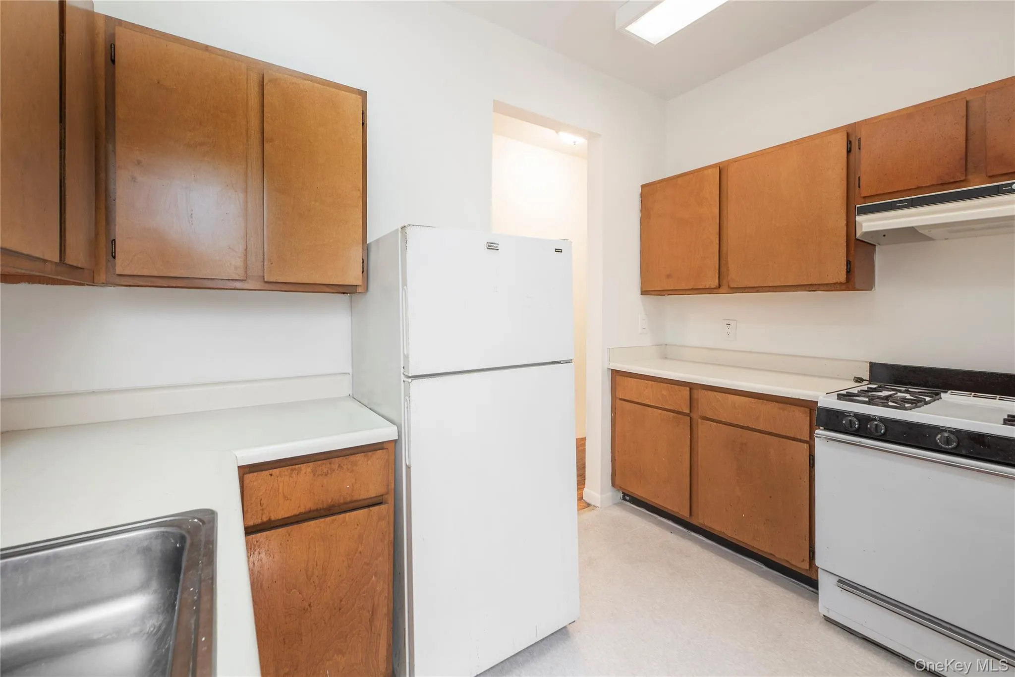 Kitchen featuring white appliances, wood finish cabinets, light countertops, and light flooring Kitchen featuring white appliances, wood finish cabinets, light countertops, and light flooring