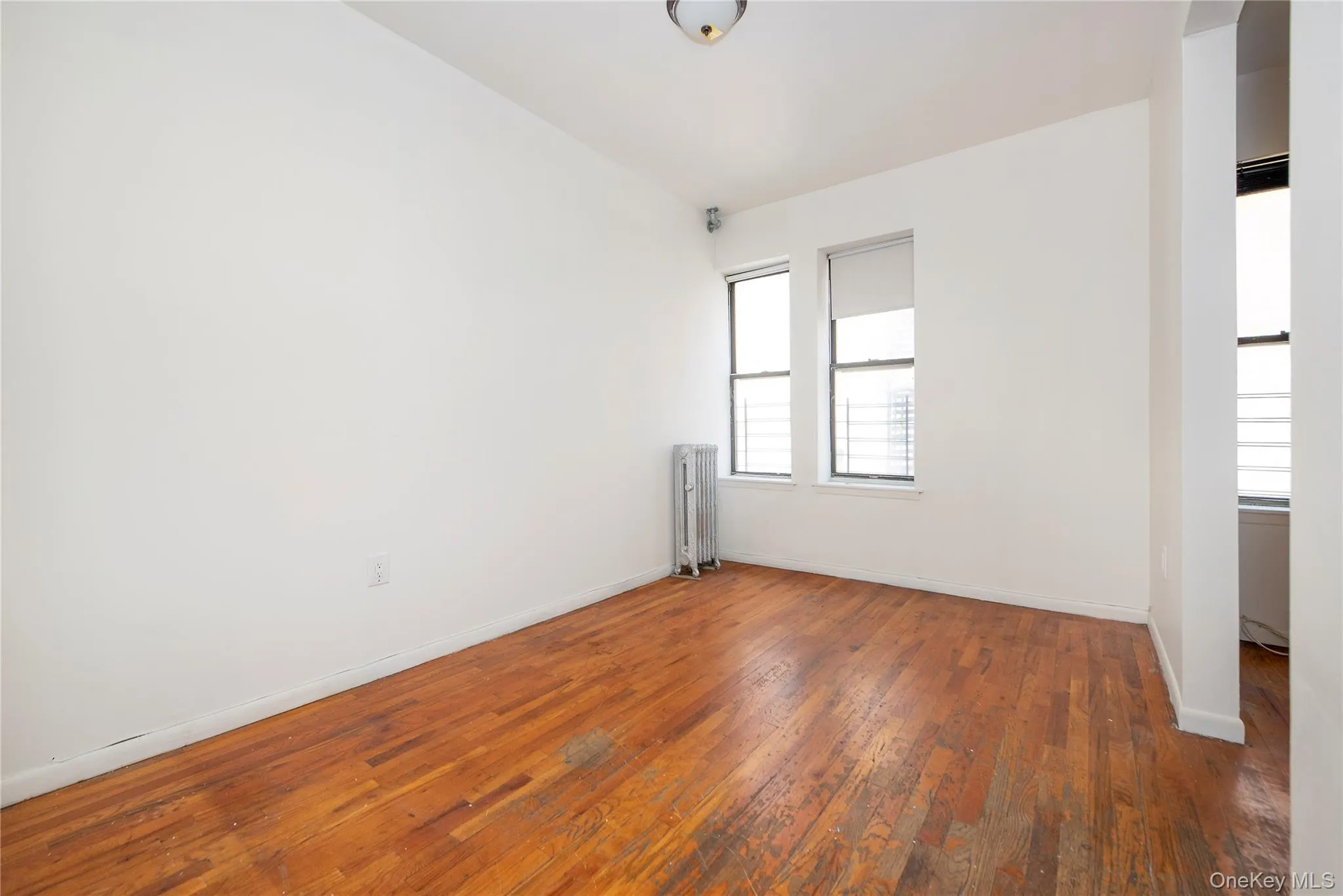 Unfurnished dining room with hardwood / wood-style floors and radiator heating unit view from hallway Unfurnished dining room with hardwood / wood-style floors and radiator heating unit view from hallway