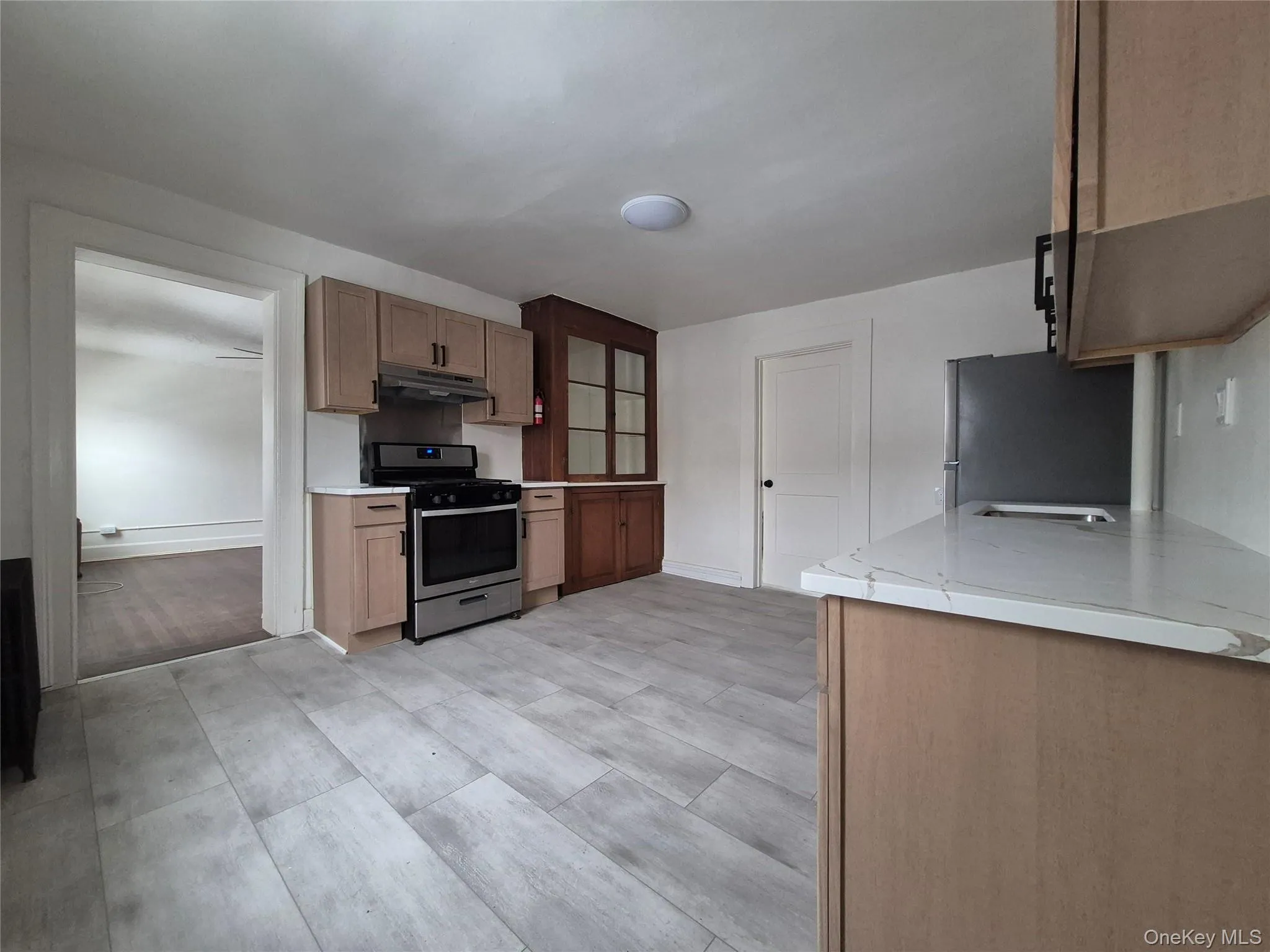 Kitchen with stainless steel appliances, glass fronted cabinets, light stone countertops, and wood finish cabinetry Kitchen with stainless steel appliances, glass fronted cabinets, light stone countertops, and wood finish cabinetry
