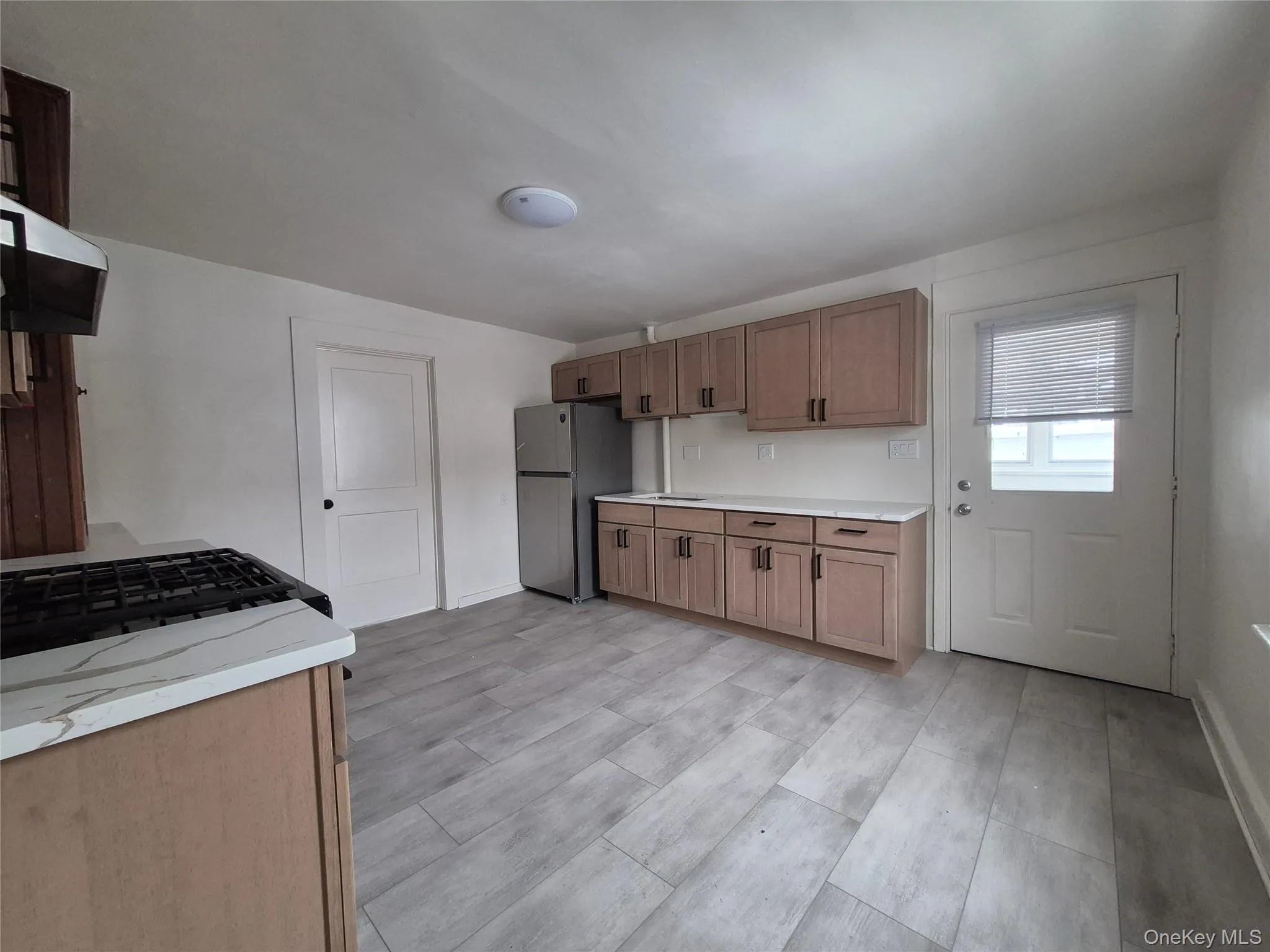 Kitchen featuring freestanding refrigerator, wood finish cabinetry, ventilation hood, and light wood-style floors Kitchen featuring freestanding refrigerator, wood finish cabinetry, ventilation hood, and light wood-style floors