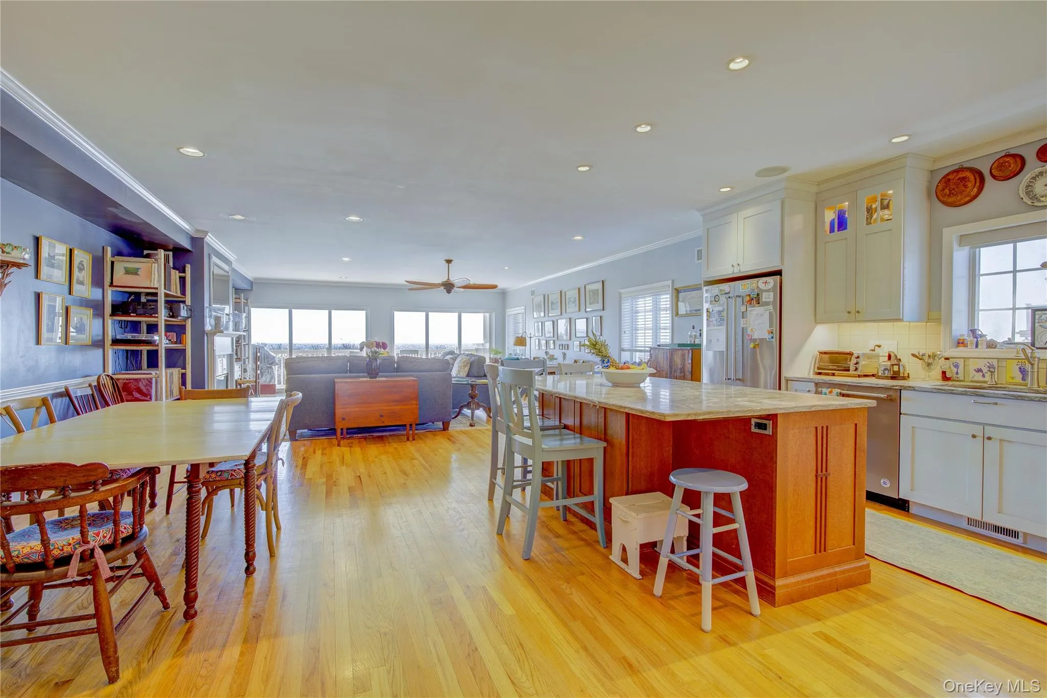 Kitchen with light wood-style flooring, ornamental molding, stainless steel appliances, a kitchen island, and tasteful backsplash Kitchen with light wood-style flooring, ornamental molding, stainless steel appliances, a kitchen island, and tasteful backsplash