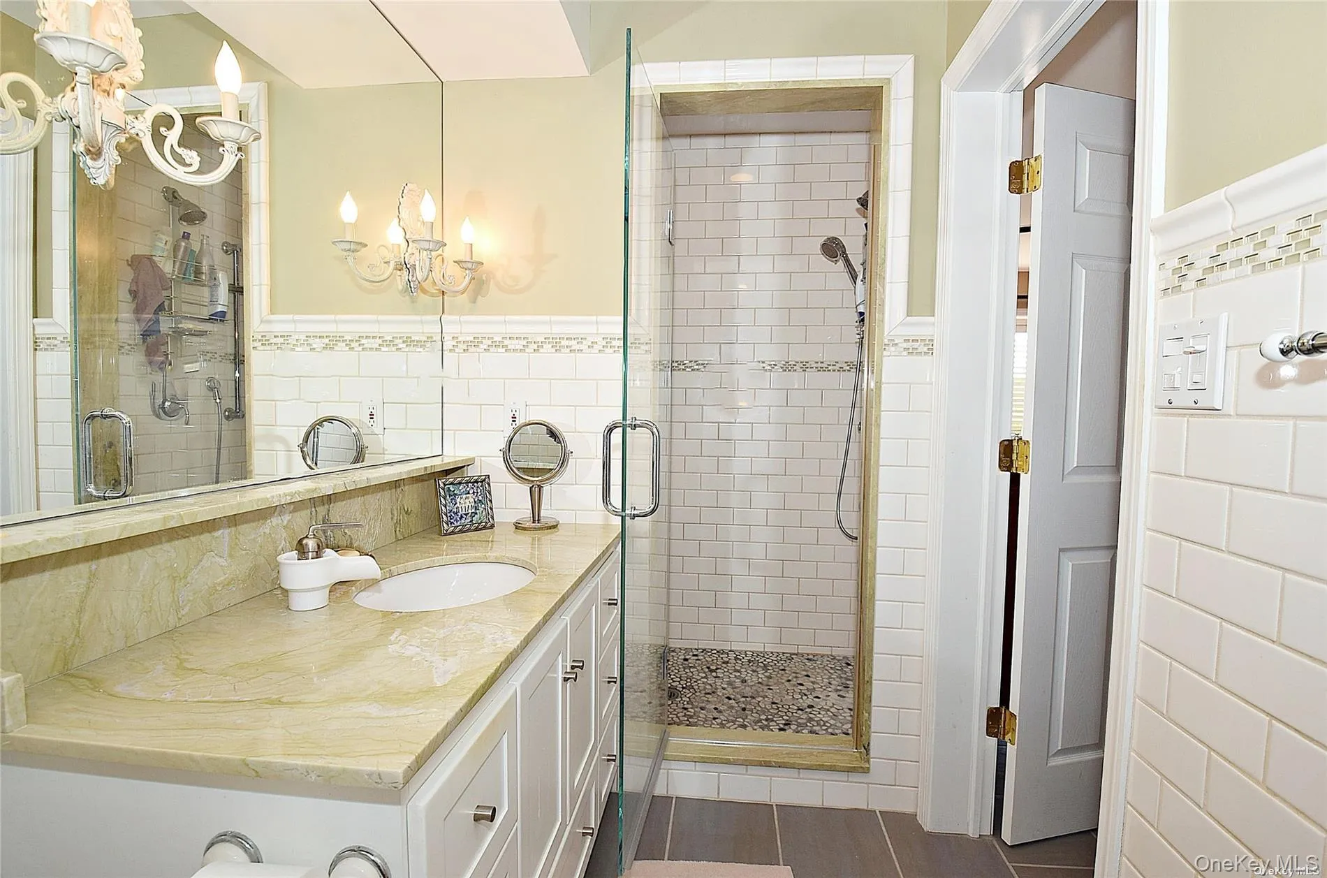 Bathroom featuring vanity, tile walls, a notable chandelier, and a shower with shower door Bathroom featuring vanity, tile walls, a notable chandelier, and a shower with shower door