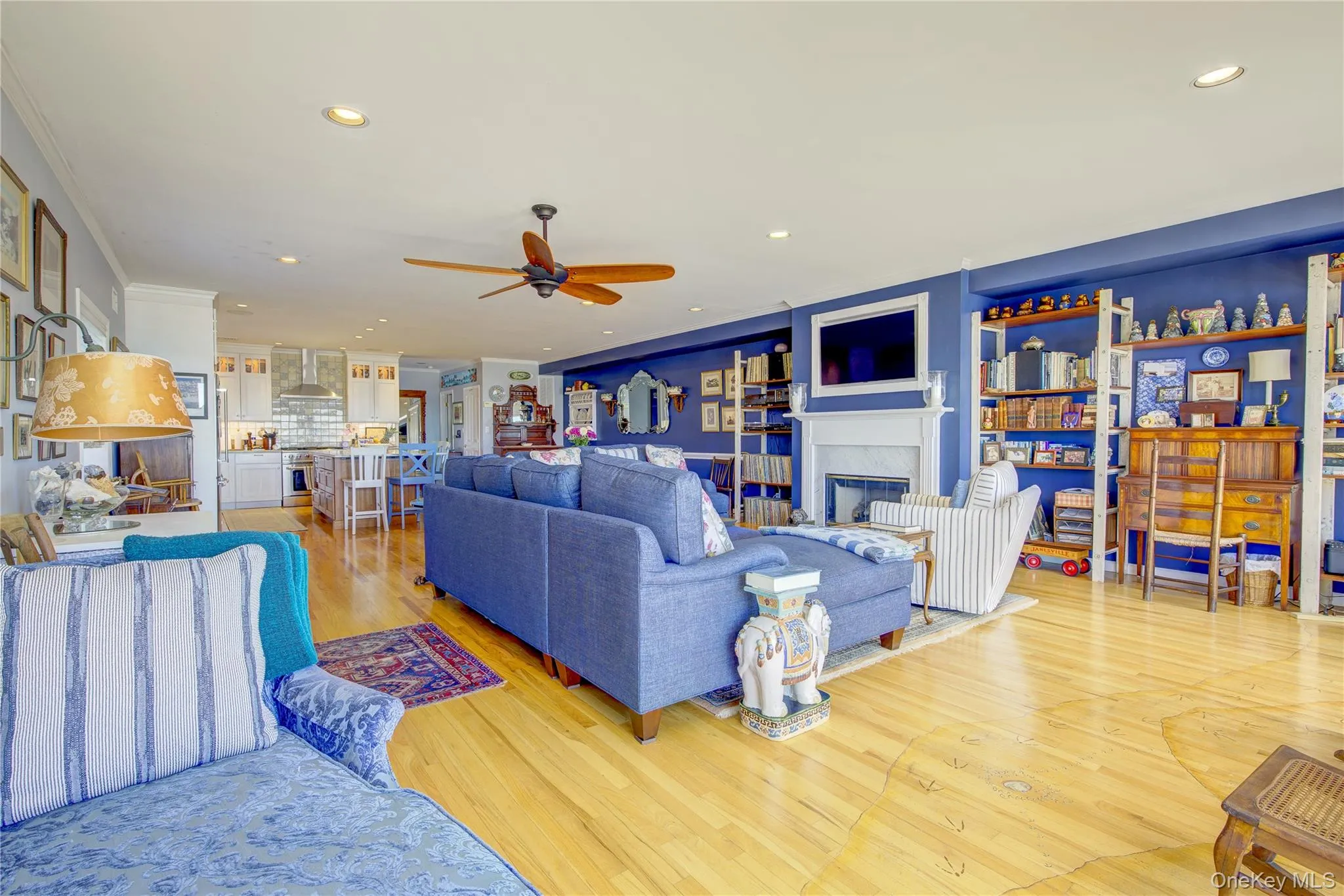Living area featuring a glass covered fireplace, light wood-style floors, recessed lighting, and a ceiling fan Living area featuring a glass covered fireplace, light wood-style floors, recessed lighting, and a ceiling fan