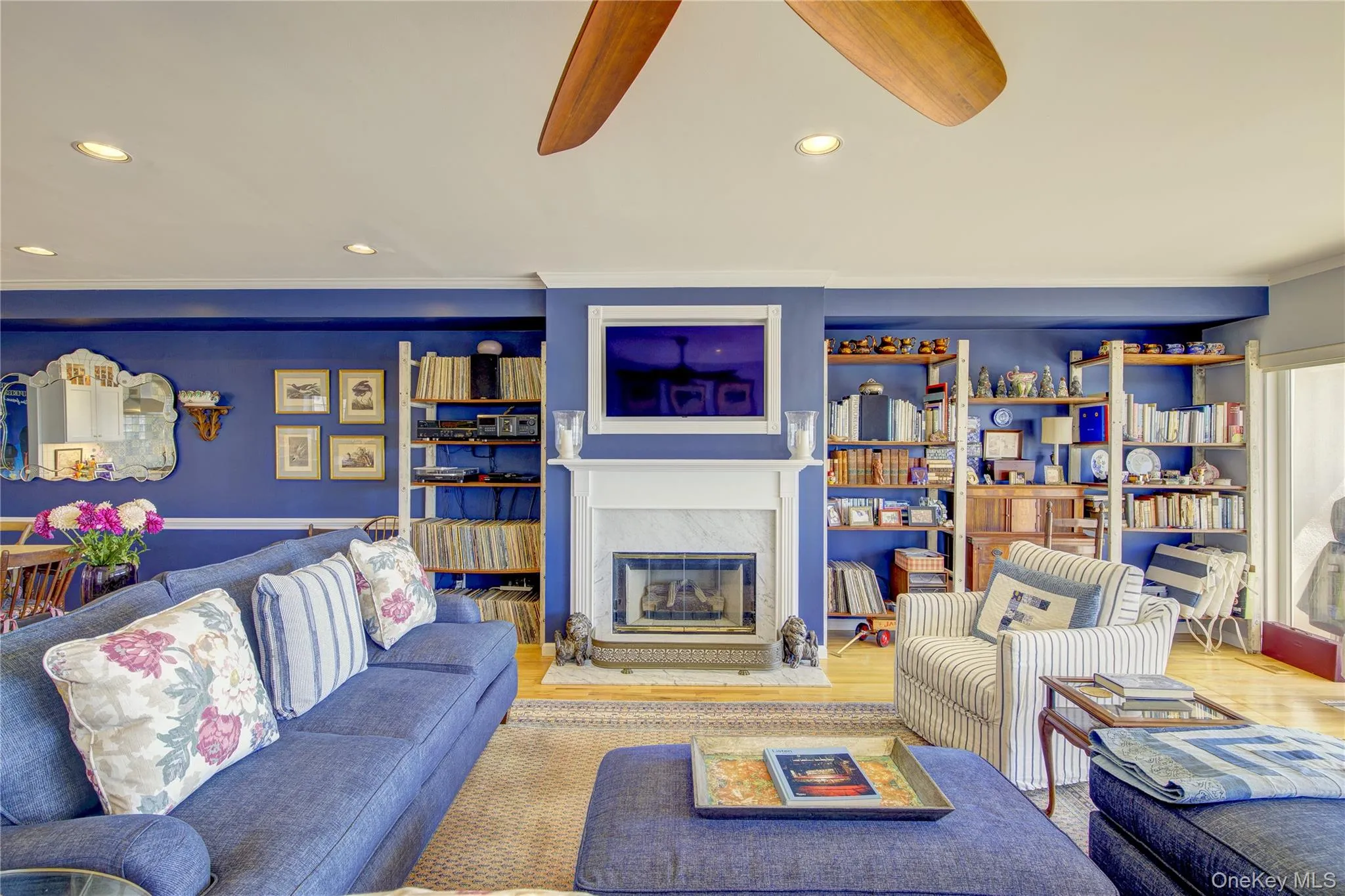 Living area with recessed lighting, ornamental molding, a ceiling fan, a fireplace, and wood finished floors Living area with recessed lighting, ornamental molding, a ceiling fan, a fireplace, and wood finished floors