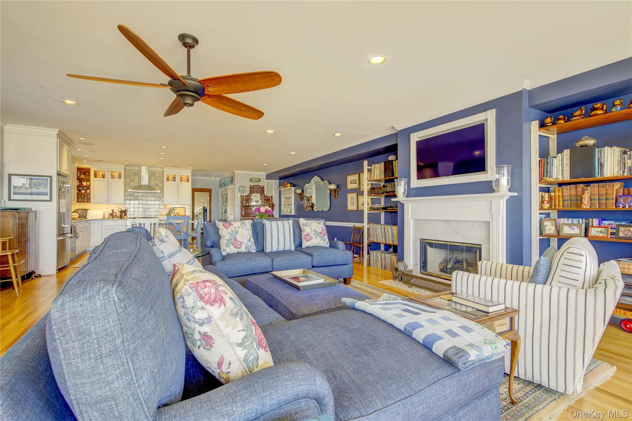 Living room with light wood finished floors, a high end fireplace, ceiling fan, and recessed lighting Living room with light wood finished floors, a high end fireplace, ceiling fan, and recessed lighting