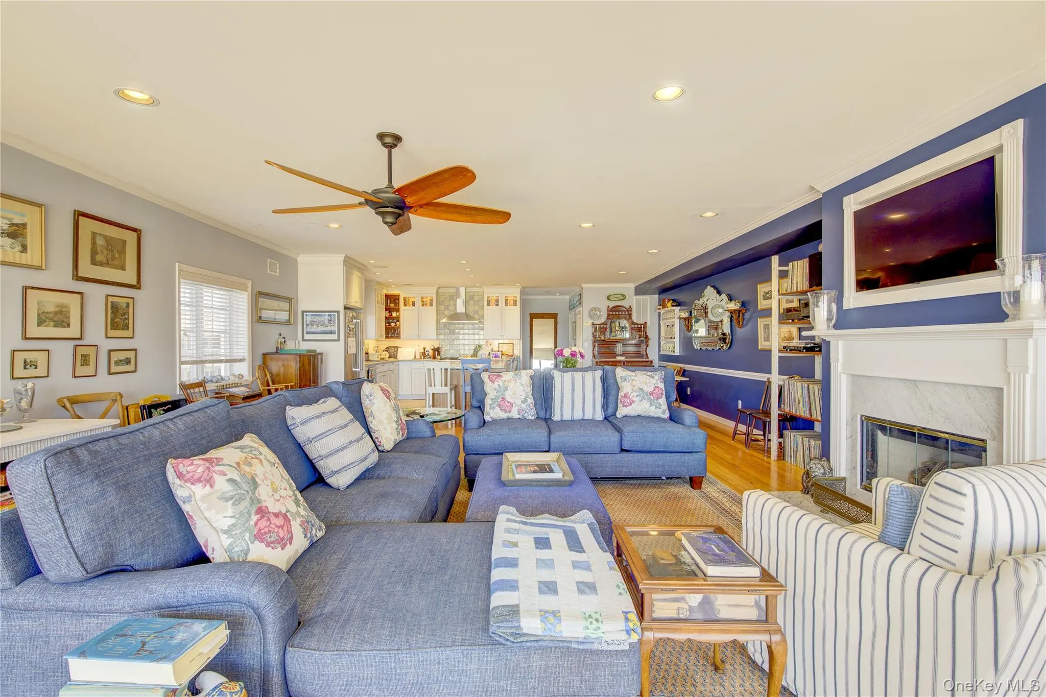 Living area featuring crown molding, a premium fireplace, recessed lighting, ceiling fan, and wood finished floors Living area featuring crown molding, a premium fireplace, recessed lighting, ceiling fan, and wood finished floors