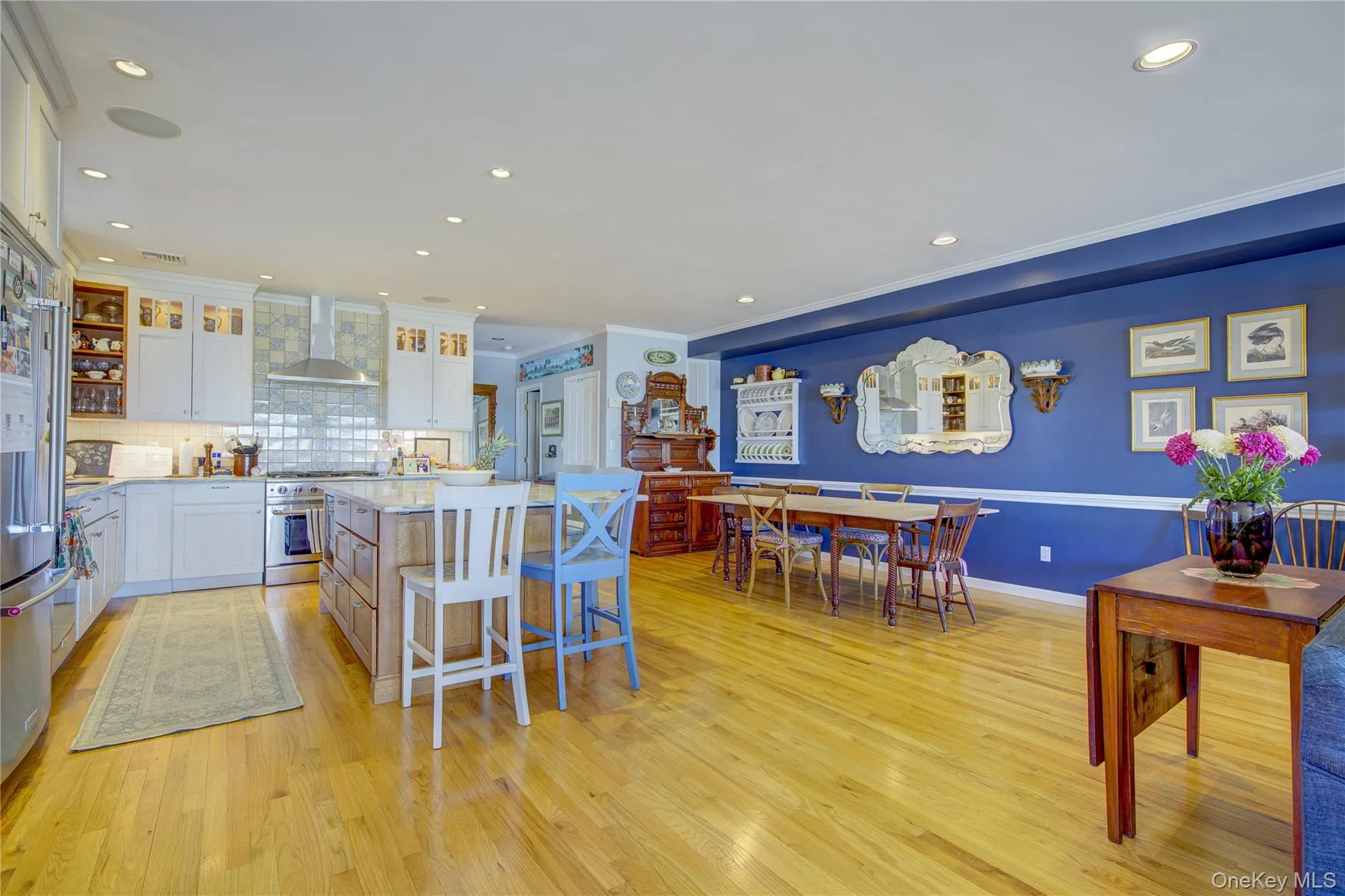 Kitchen featuring light wood-style flooring, wall chimney exhaust hood, white cabinetry, stainless steel range, and a center island Kitchen featuring light wood-style flooring, wall chimney exhaust hood, white cabinetry, stainless steel range, and a center island