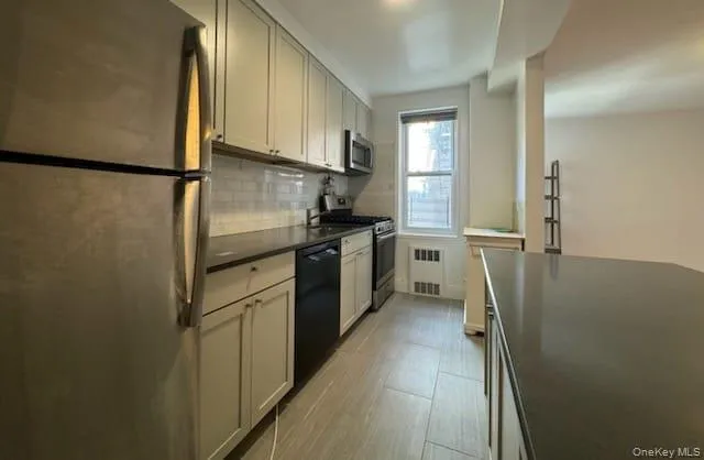 Kitchen with dark countertops, stainless steel appliances, and backsplash Kitchen with dark countertops, stainless steel appliances, and backsplash