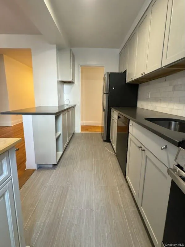 Kitchen featuring light wood-style flooring, stainless steel appliances, decorative backsplash, and open shelves Kitchen featuring light wood-style flooring, stainless steel appliances, decorative backsplash, and open shelves