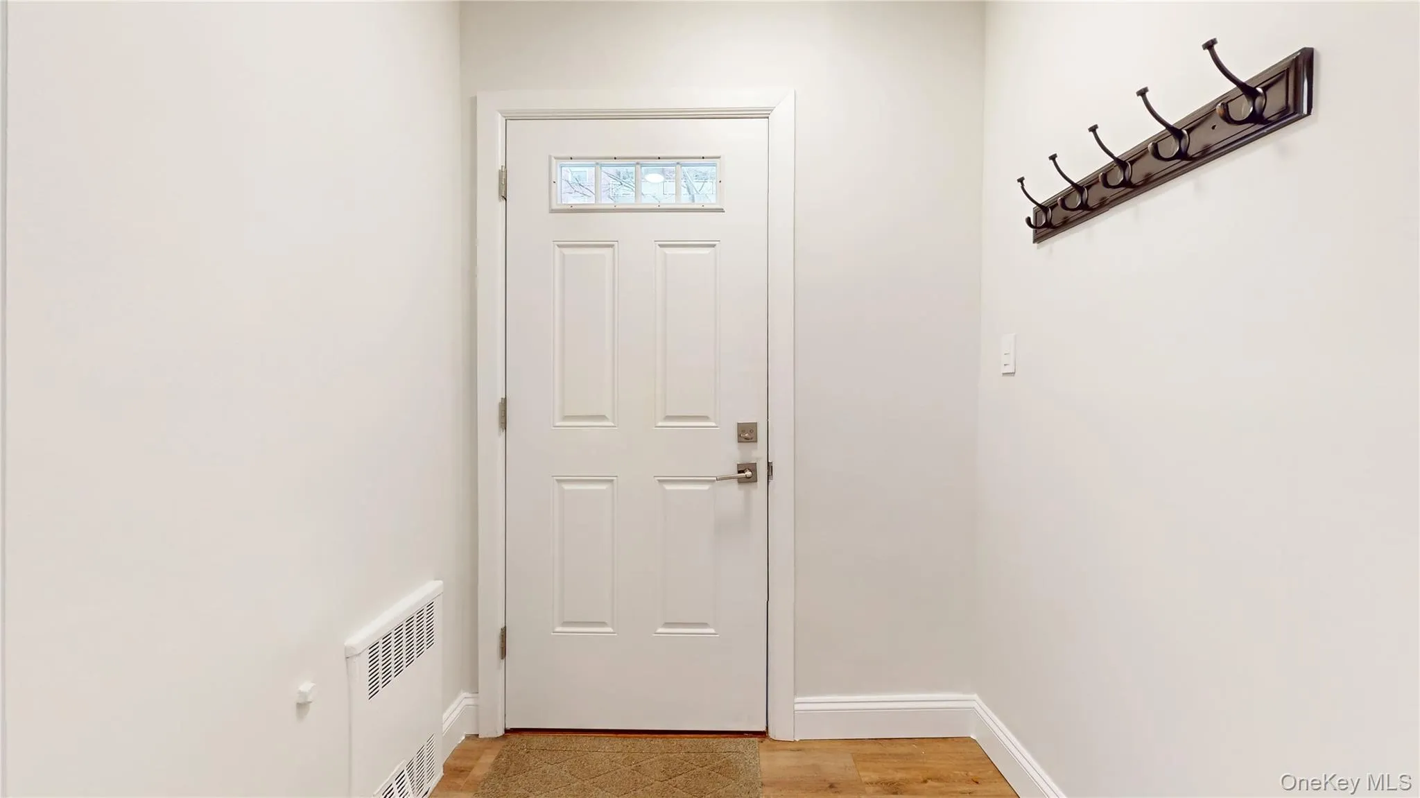 Doorway featuring radiator and wood finished floors Doorway featuring radiator and wood finished floors
