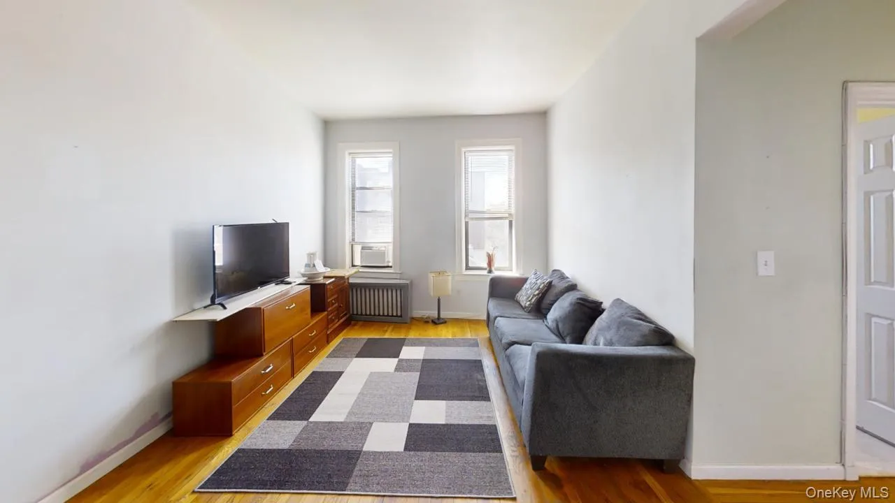 Living room featuring radiator, baseboards, and light wood-type flooring Living room featuring radiator, baseboards, and light wood-type flooring