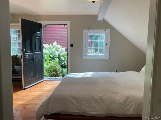 Primary Bedroom with light wood-type flooring, lofted ceiling with beams, a ceiling fan, and access to exterior Primary Bedroom with light wood-type flooring, lofted ceiling with beams, a ceiling fan, and access to exterior