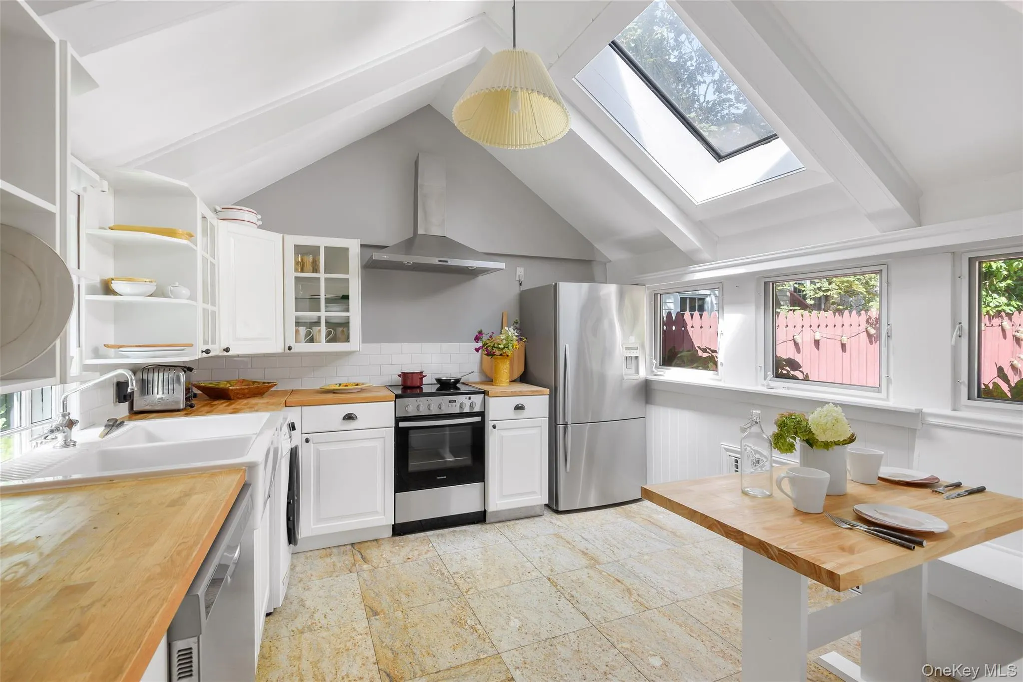 Kitchen featuring butcher block countertops, a skylight, stainless steel appliances, glass insert cabinets, and open shelves Kitchen featuring butcher block countertops, a skylight, stainless steel appliances, glass insert cabinets, and open shelves