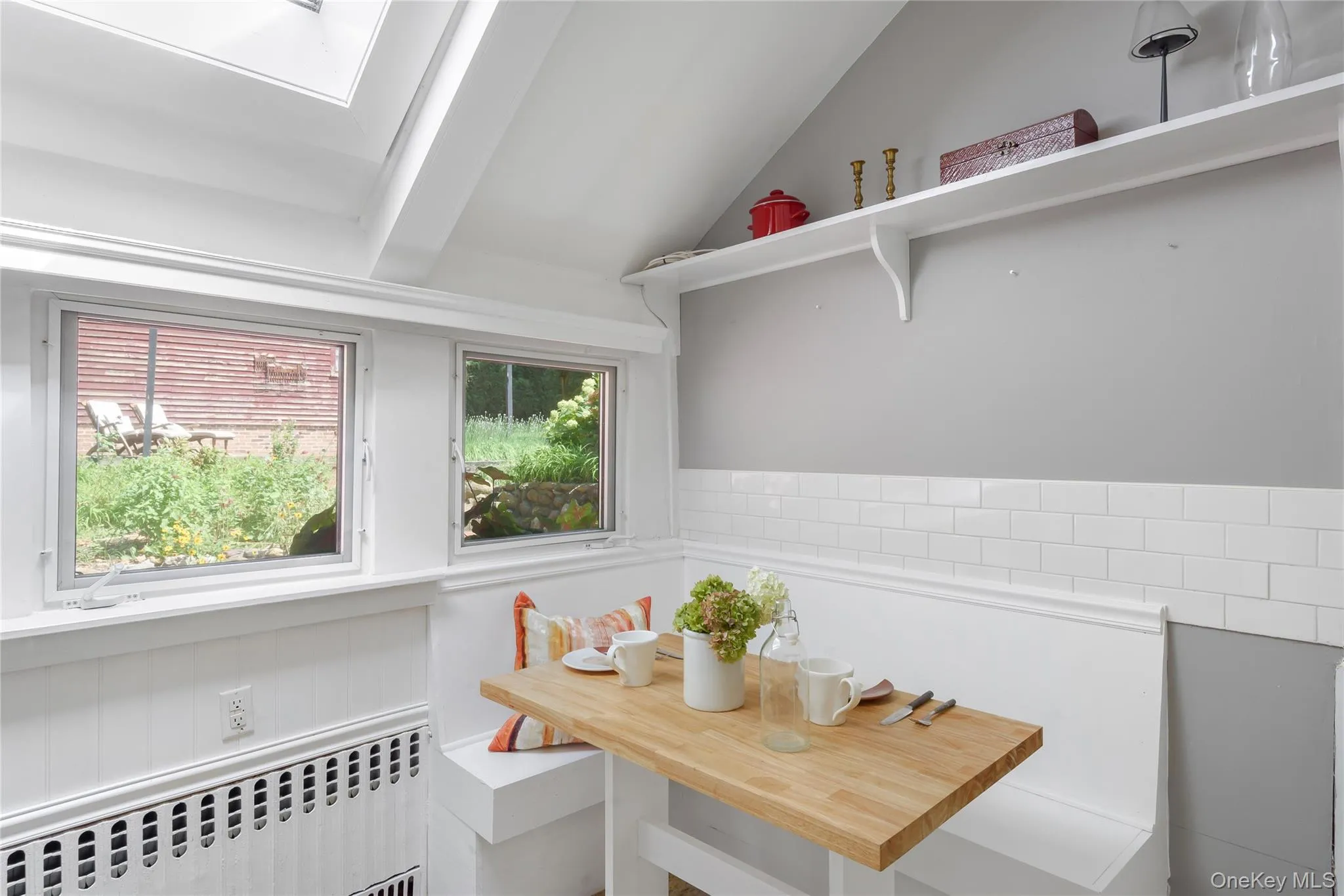 Dining area featuring radiator heating unit, breakfast area, a skylight, wainscoting, and a baseboard radiator Dining area featuring radiator heating unit, breakfast area, a skylight, wainscoting, and a baseboard radiator