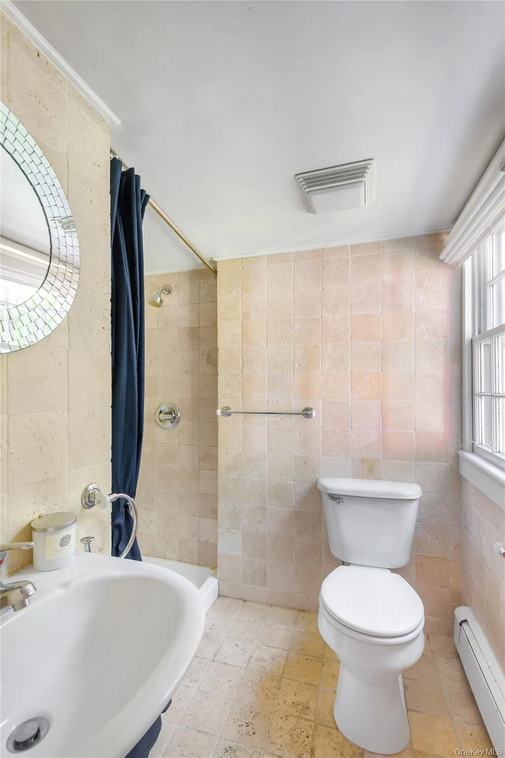 Bathroom featuring a stall shower, tile walls, and a baseboard heating unit Bathroom featuring a stall shower, tile walls, and a baseboard heating unit