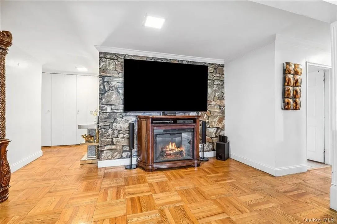 Living room featuring crown molding, a fireplace, and light parquet flooring Living room featuring crown molding, a fireplace, and light parquet flooring