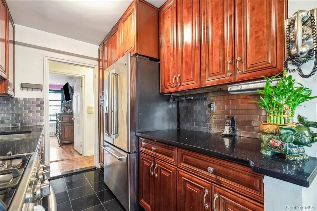 Kitchen with dark stone counters, backsplash, range, dark tile flooring, and high end refrigerator Kitchen with dark stone counters, backsplash, range, dark tile flooring, and high end refrigerator