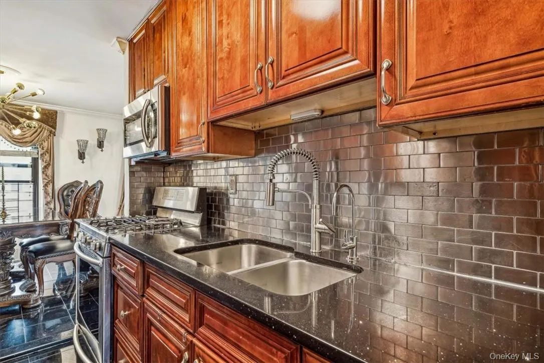 Kitchen with dark stone counters, stainless steel appliances, backsplash, crown molding, and sink Kitchen with dark stone counters, stainless steel appliances, backsplash, crown molding, and sink