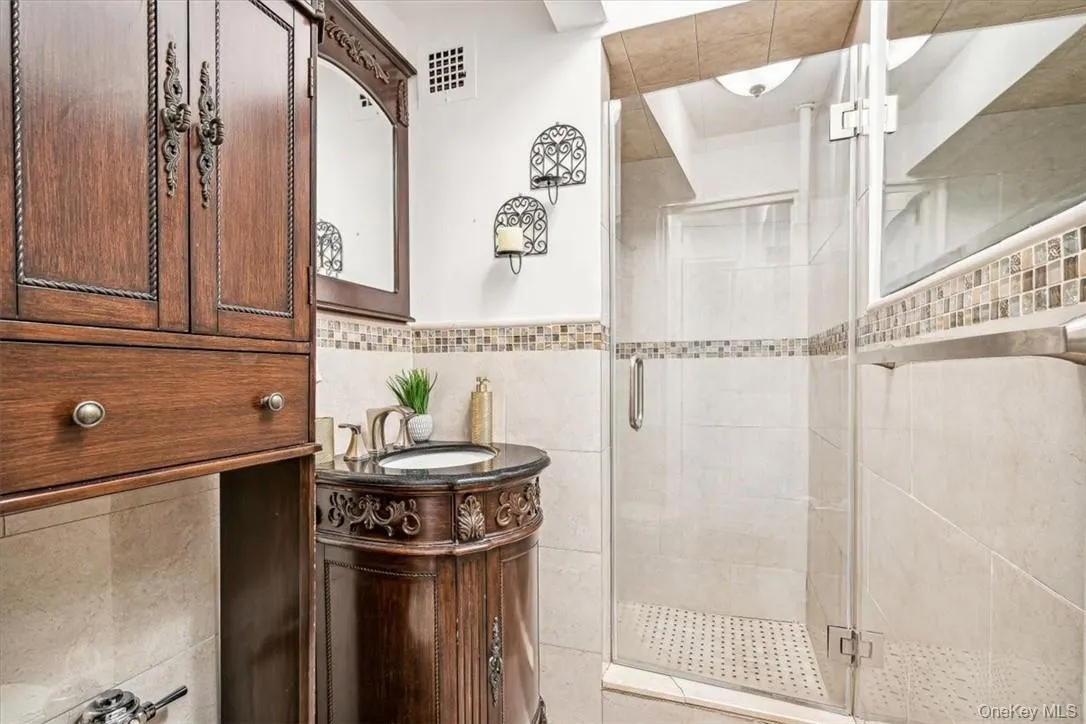 Bathroom featuring backsplash, walk in shower, oversized vanity, and tile walls Bathroom featuring backsplash, walk in shower, oversized vanity, and tile walls