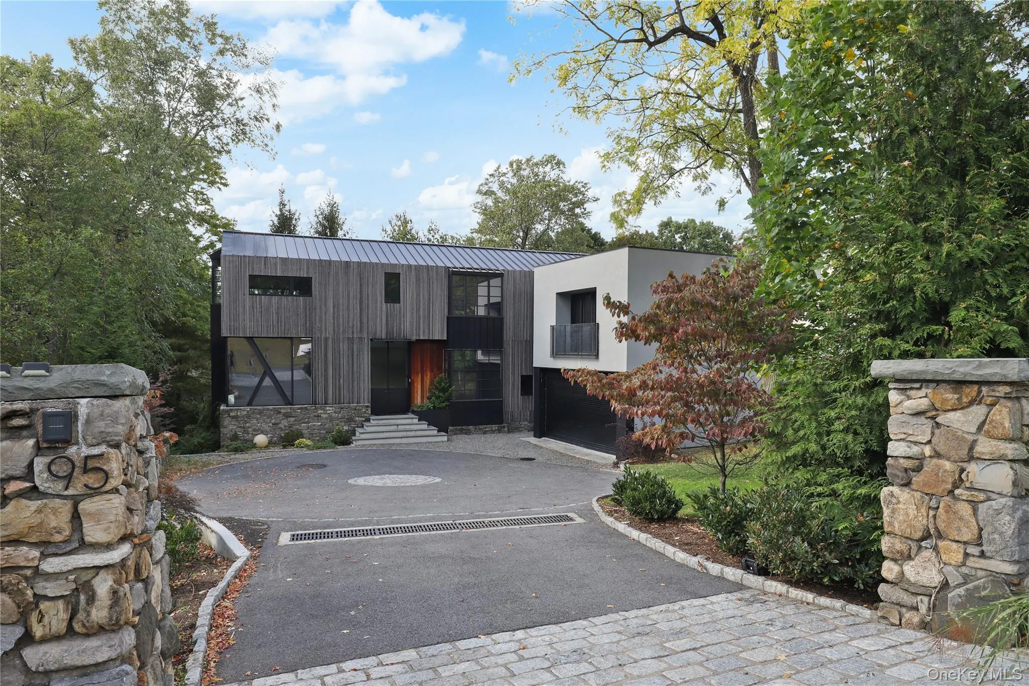 A private approach - introduces the home's modern facade through stone pillars and circular driveway A private approach - introduces the home's modern facade through stone pillars and circular driveway
