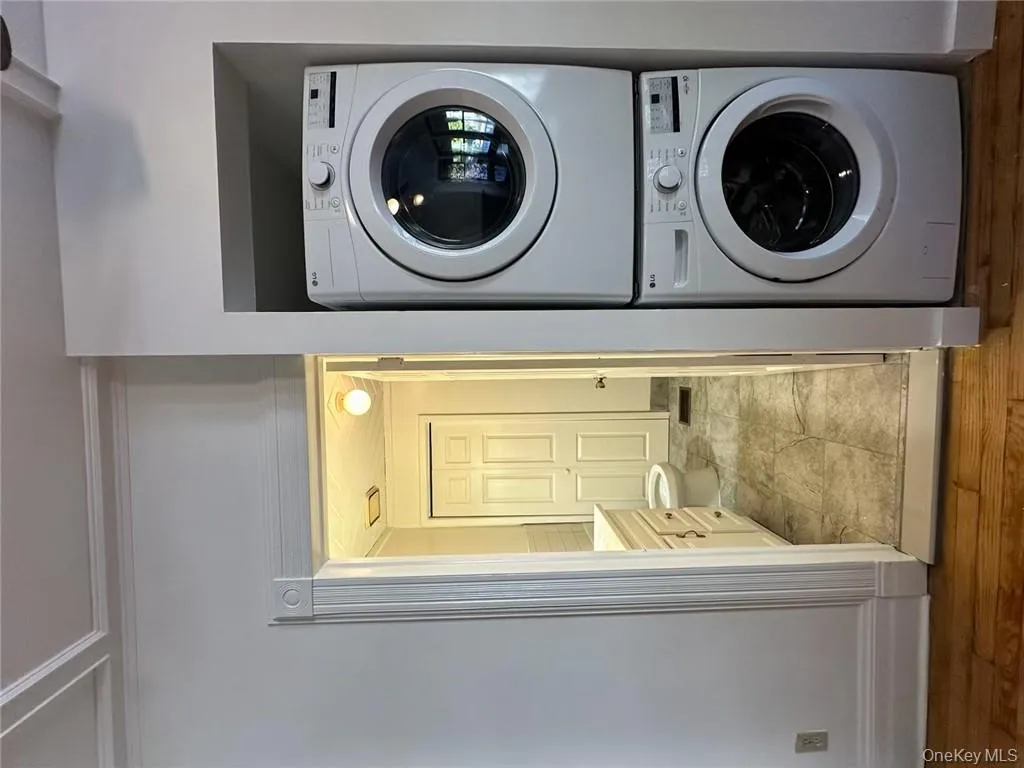 Laundry area featuring stacked washer / drying machine and light hardwood / wood-style floors Laundry area featuring stacked washer / drying machine and light hardwood / wood-style floors