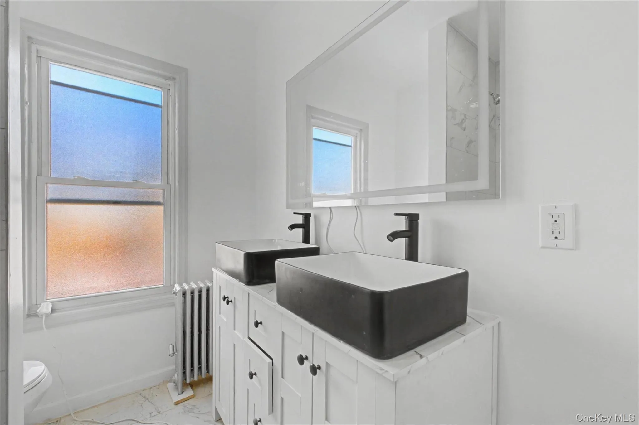 bathroom featuring stunning marble-style tile, a deep soaking tub, and dual vessel sinks bathroom featuring stunning marble-style tile, a deep soaking tub, and dual vessel sinks