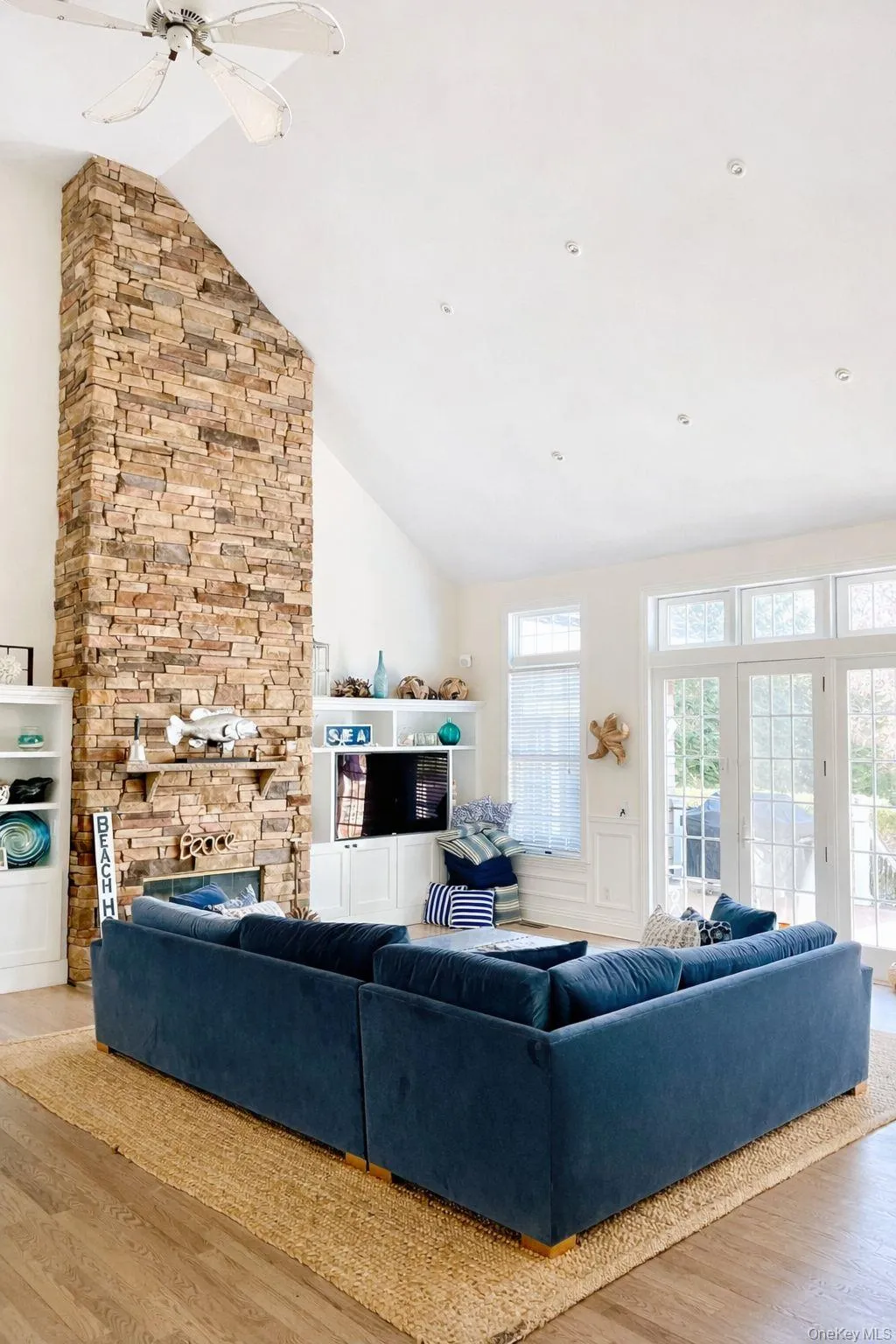 Living area with light wood-style flooring, vaulted ceiling, & stone fireplace Living area with light wood-style flooring, vaulted ceiling, & stone fireplace