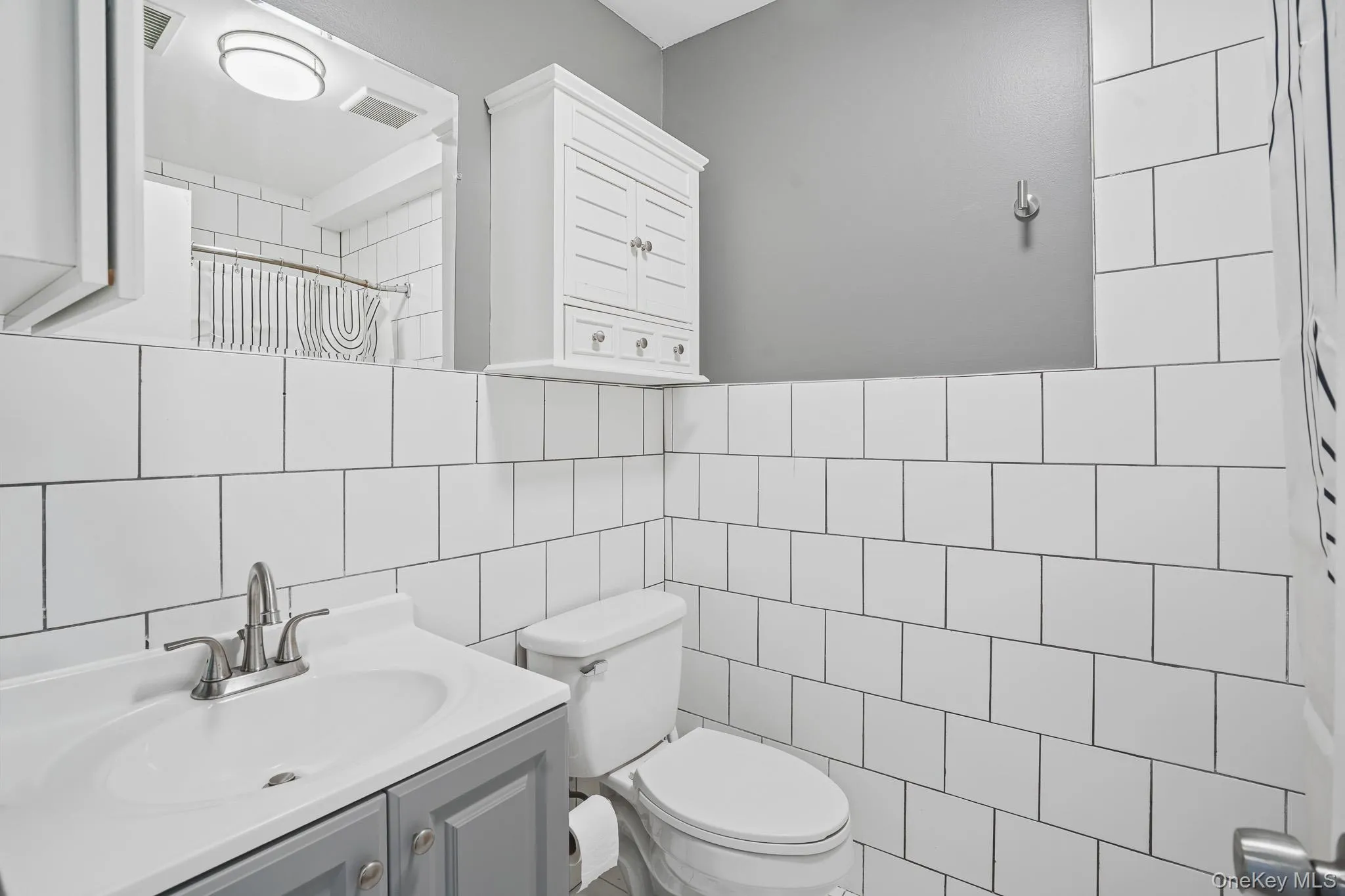Bathroom with curtained shower, vanity, and tile walls Bathroom with curtained shower, vanity, and tile walls