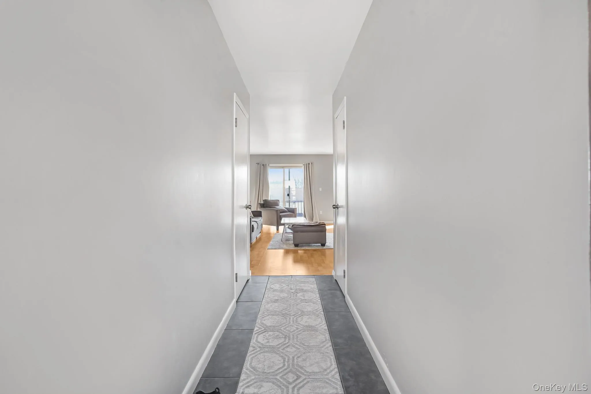Hallway with baseboards and dark tile patterned flooring Hallway with baseboards and dark tile patterned flooring
