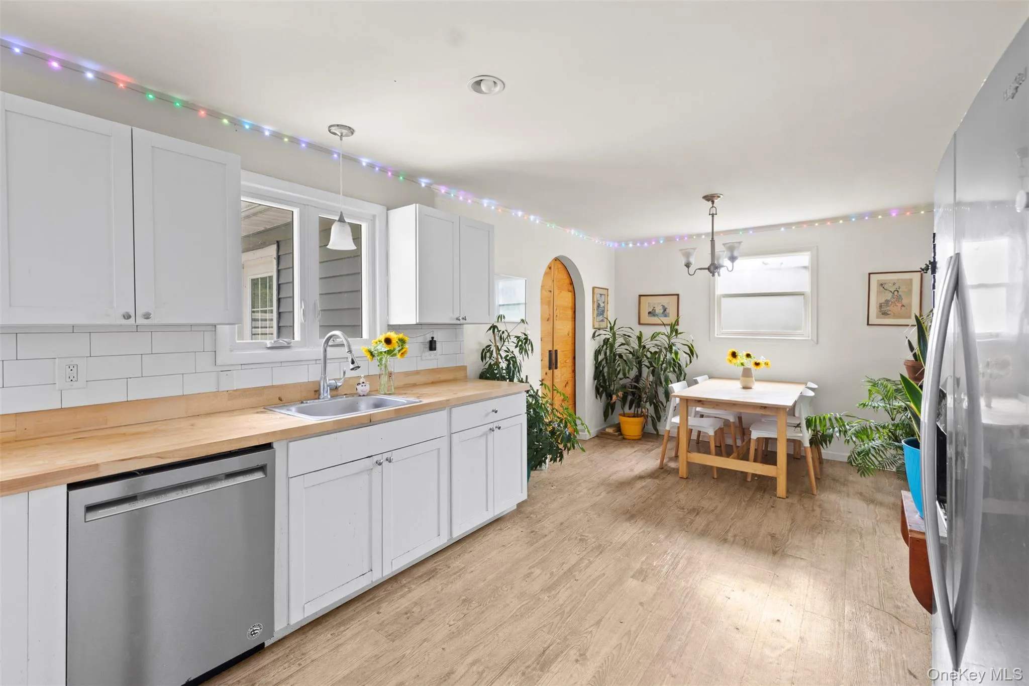 Kitchen featuring appliances with stainless steel finishes, butcher block counters, light wood-style floors, backsplash, and a chandelier Kitchen featuring appliances with stainless steel finishes, butcher block counters, light wood-style floors, backsplash, and a chandelier