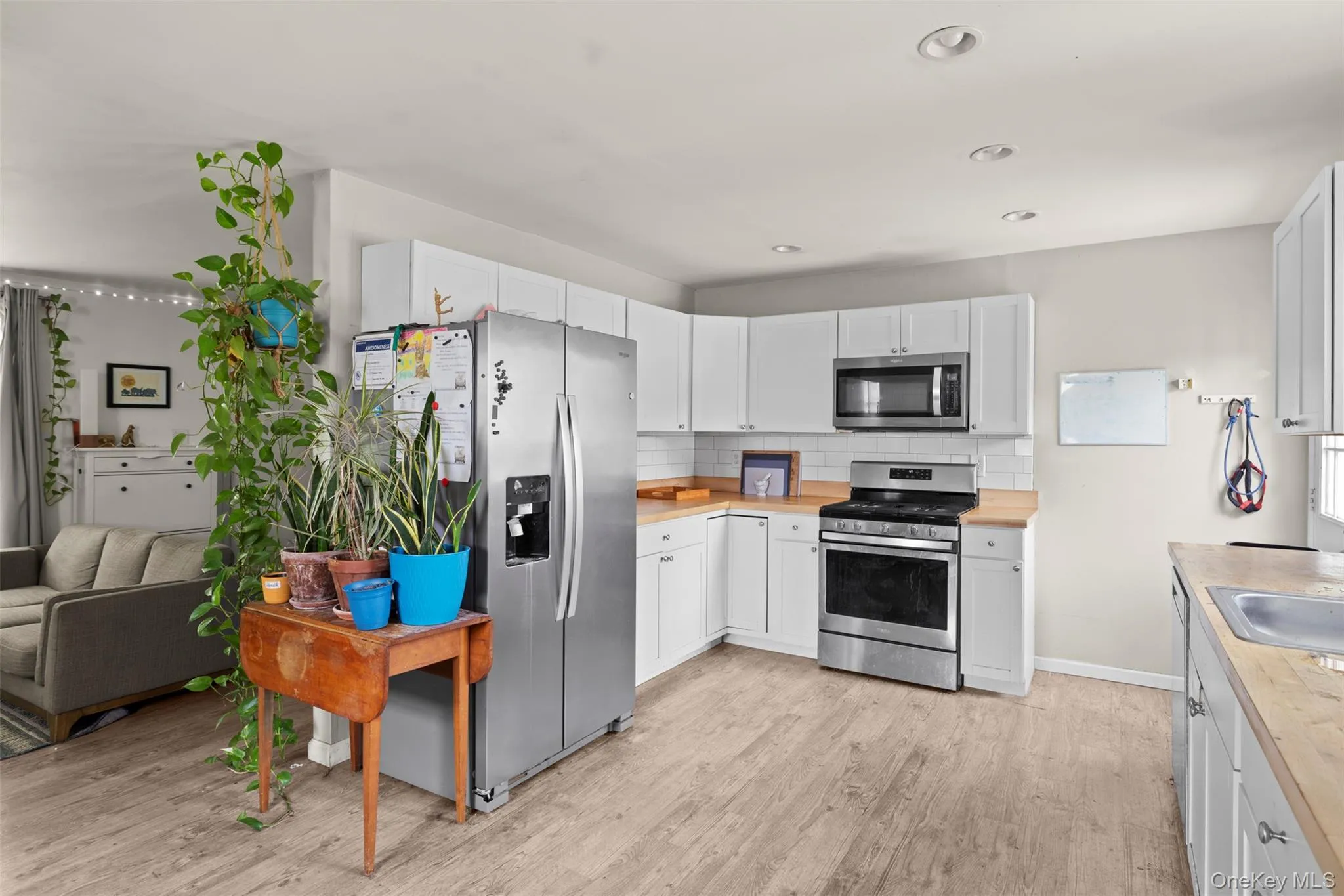 Kitchen with appliances with stainless steel finishes, light wood-style flooring, backsplash, wooden counters, and recessed lighting Kitchen with appliances with stainless steel finishes, light wood-style flooring, backsplash, wooden counters, and recessed lighting