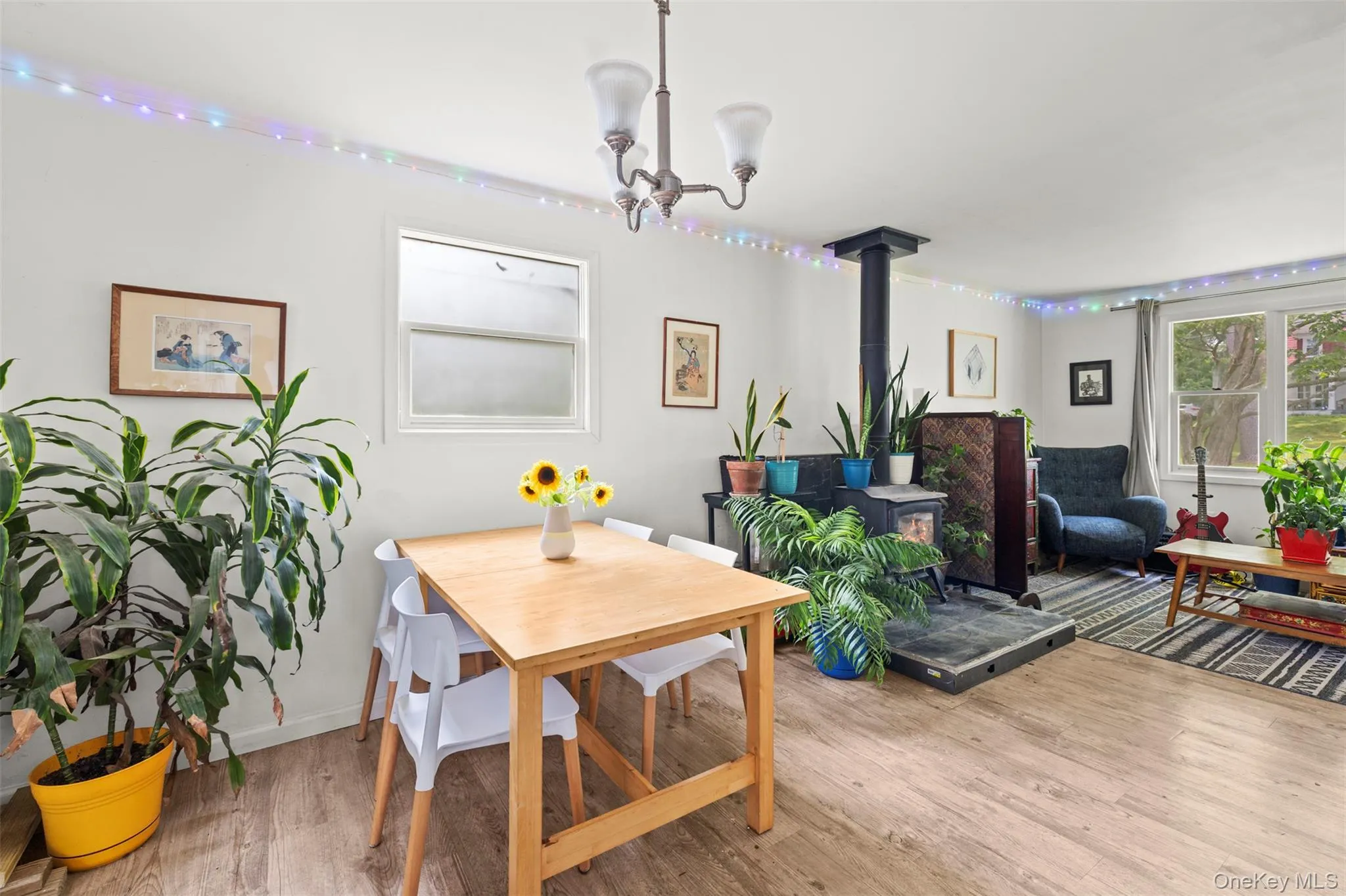 Dining space with a wood stove, a chandelier, and wood finished floors Dining space with a wood stove, a chandelier, and wood finished floors