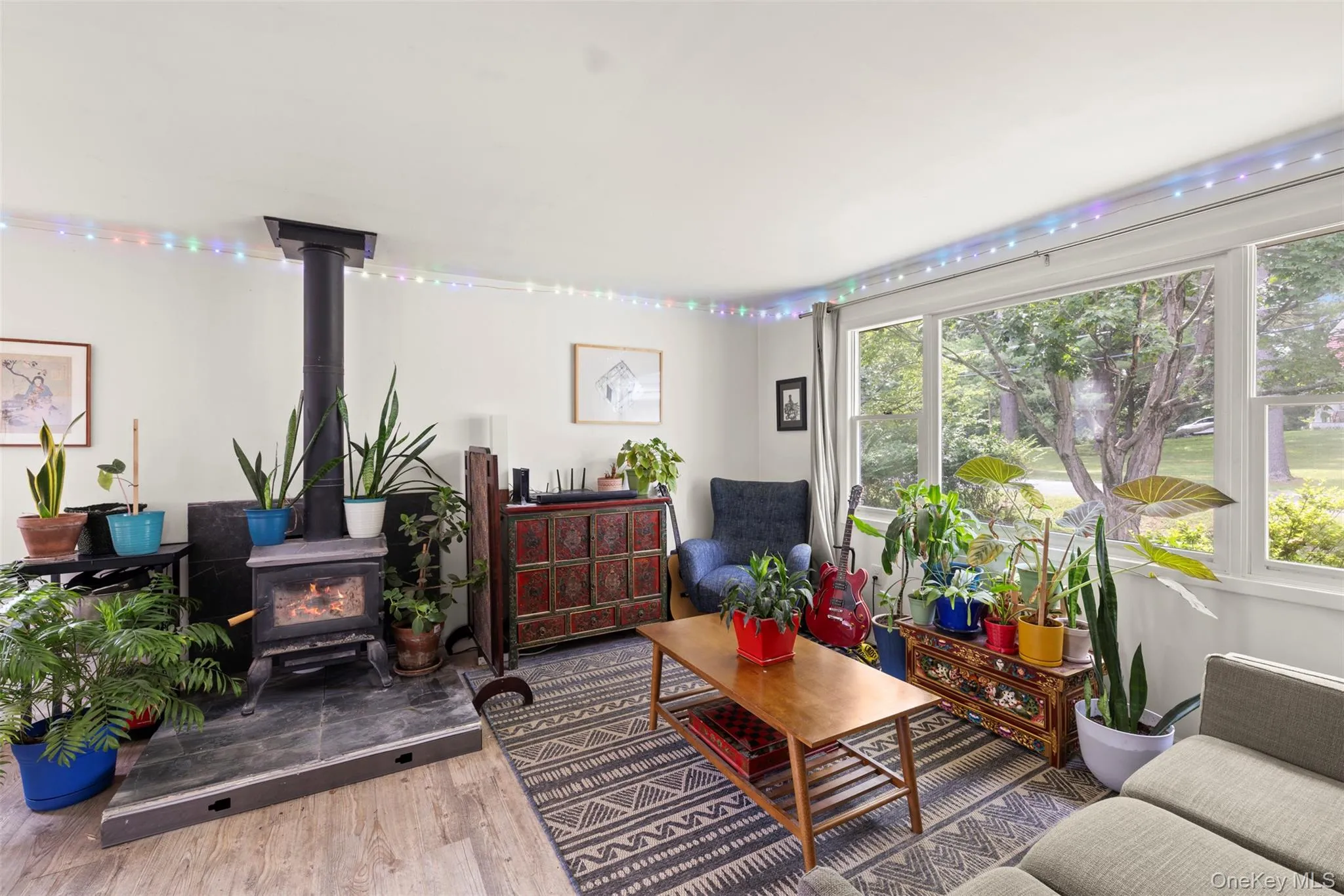Living room with a wood stove, plenty of natural light, and wood finished floors Living room with a wood stove, plenty of natural light, and wood finished floors