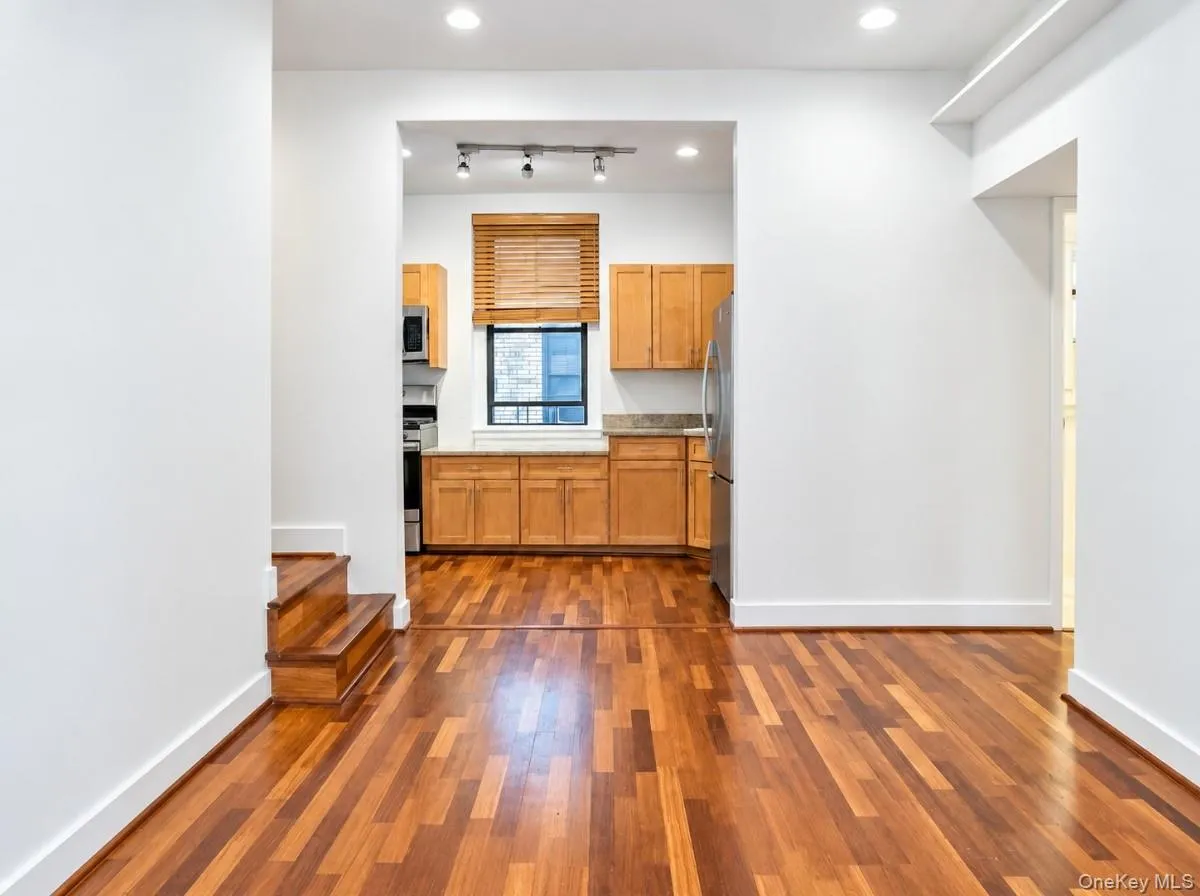Hardwood flooring throughout, recessed lighting, and a lower-level kitchen featuring wood cabinetry, stone countertops, and stainless steel appliances Hardwood flooring throughout, recessed lighting, and a lower-level kitchen featuring wood cabinetry, stone countertops, and stainless steel appliances