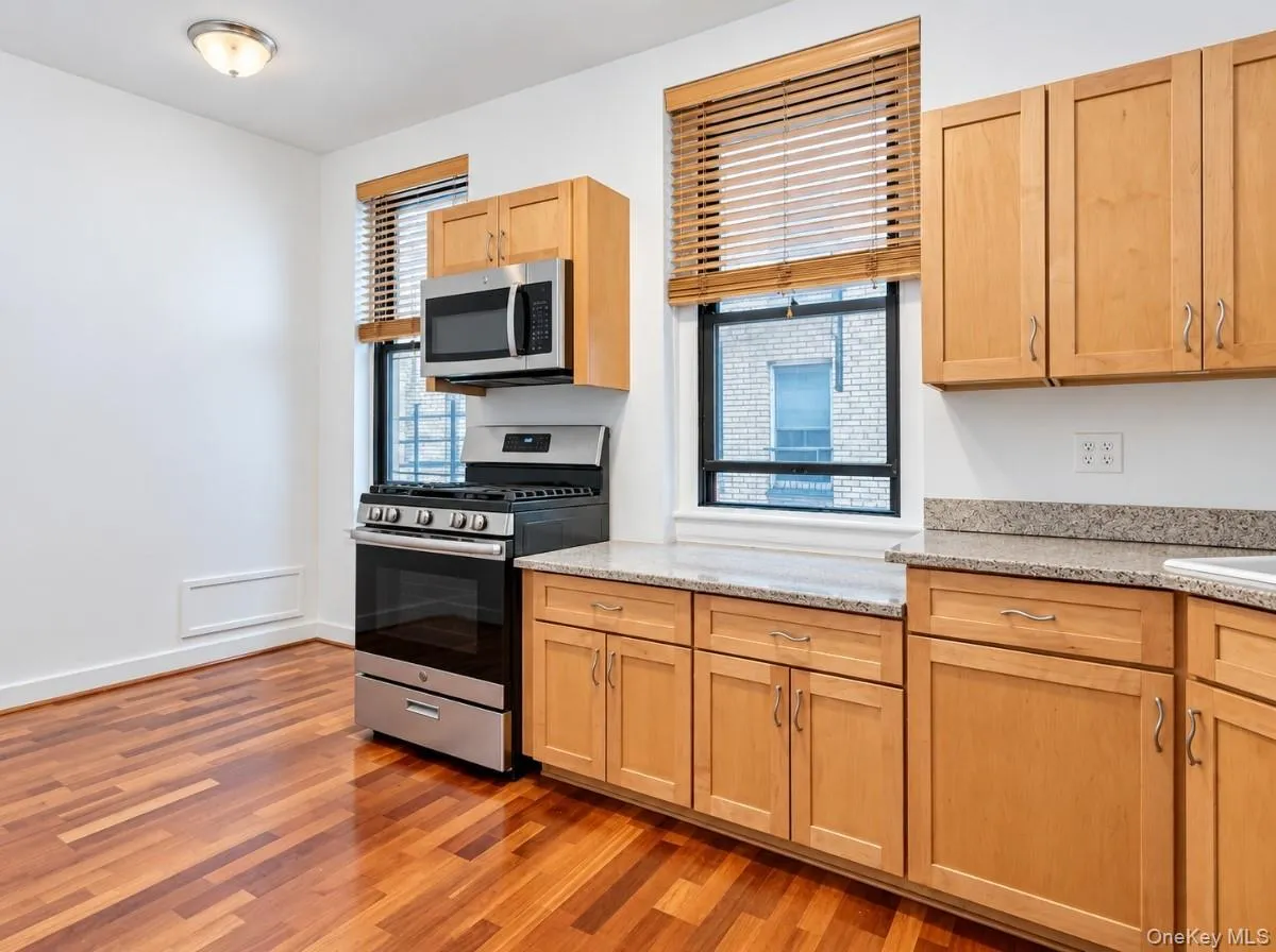 Wood-finish flooring, light wood cabinetry, stainless steel range, stainless steel microwave, and stone-finish countertops Wood-finish flooring, light wood cabinetry, stainless steel range, stainless steel microwave, and stone-finish countertops