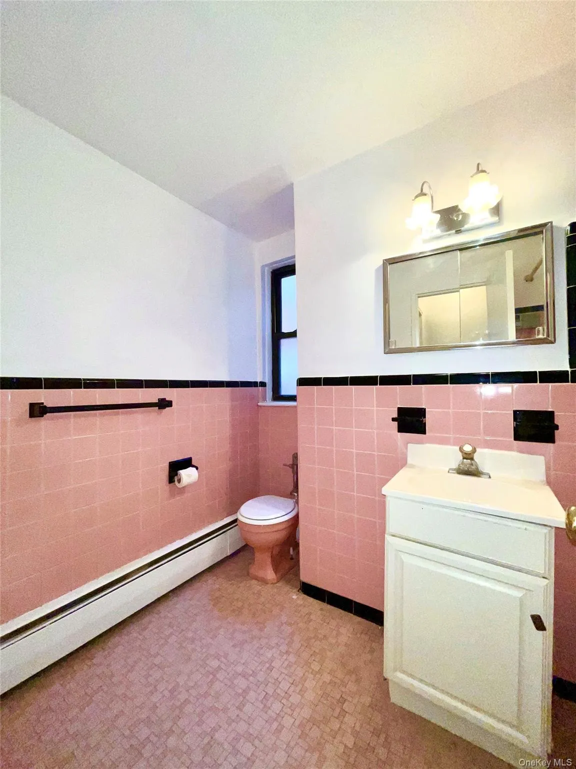 Bathroom featuring tile walls, a baseboard heating unit, a wainscoted wall, vanity, and light floors Bathroom featuring tile walls, a baseboard heating unit, a wainscoted wall, vanity, and light floors