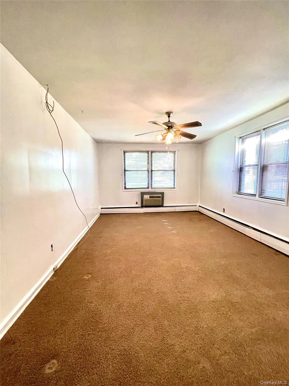 Carpeted bedroom featuring ceiling fan and a baseboard heating unit Carpeted bedroom featuring ceiling fan and a baseboard heating unit