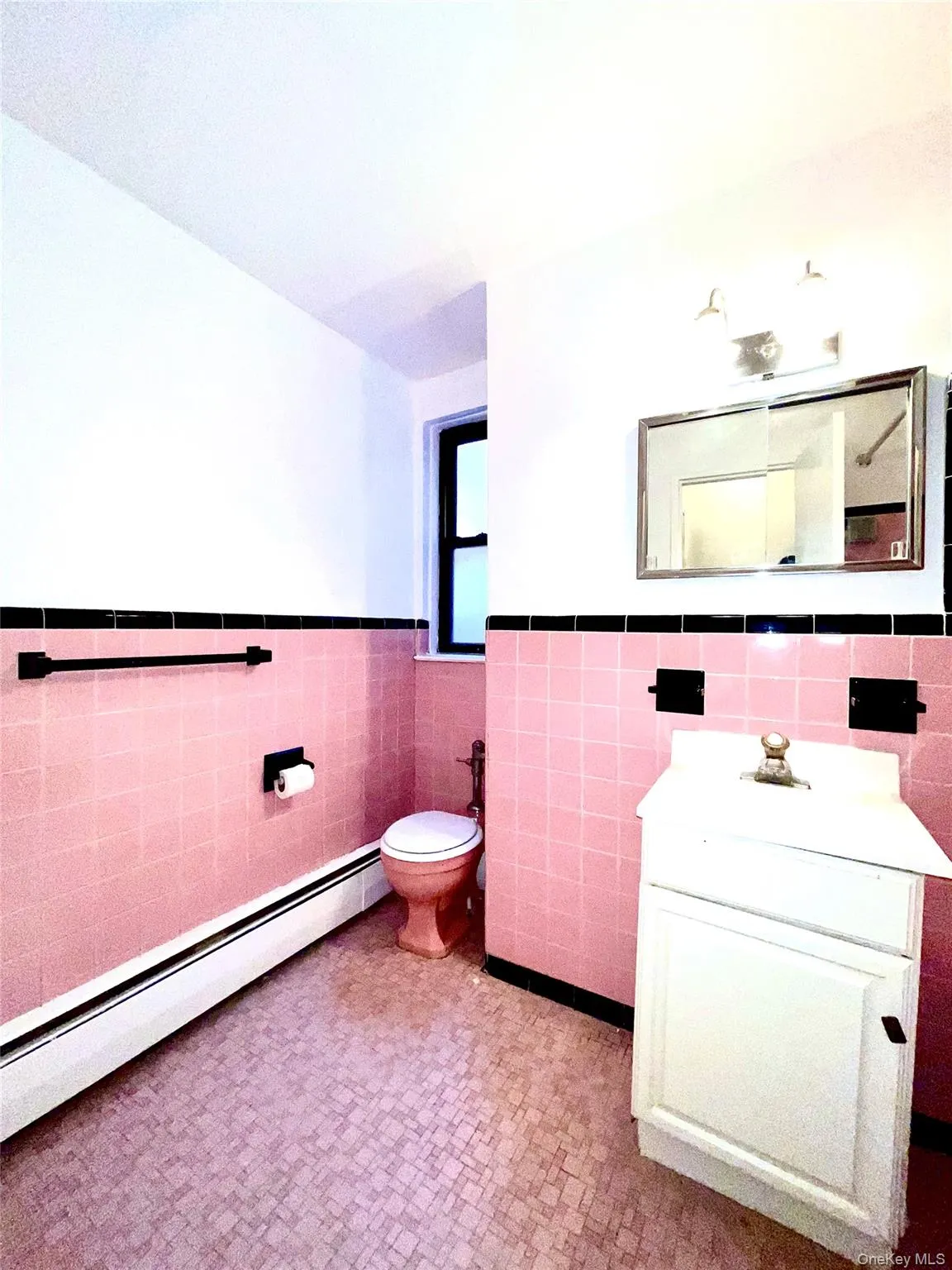 Half bath featuring tile walls, a baseboard heating unit, wainscoting, vanity, and tile patterned floors Half bath featuring tile walls, a baseboard heating unit, wainscoting, vanity, and tile patterned floors