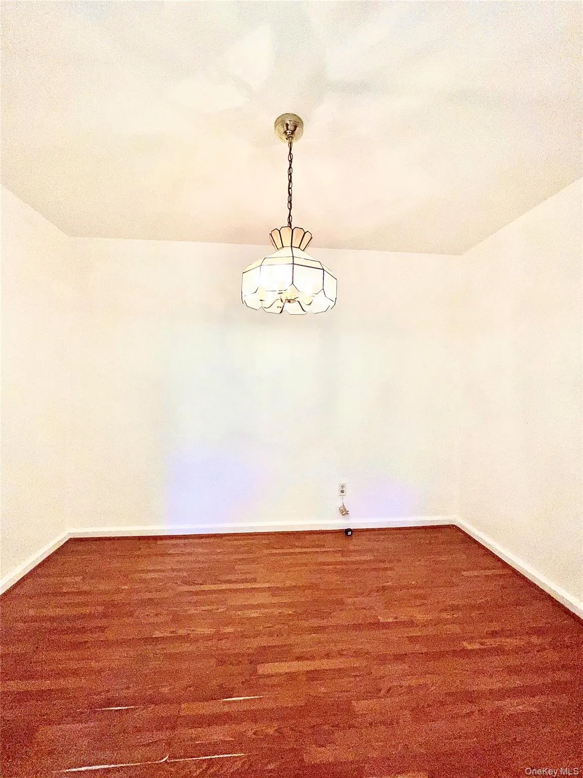Spare room featuring baseboards and dark wood-style flooring Spare room featuring baseboards and dark wood-style flooring