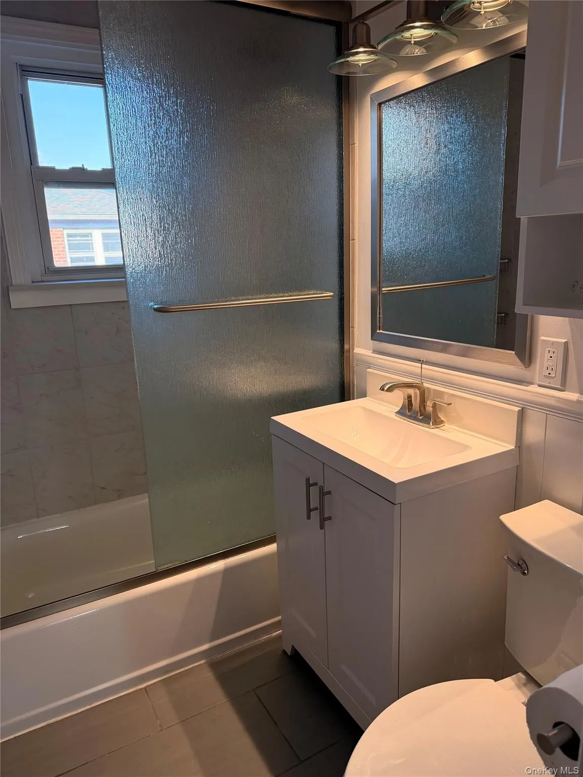 Full bath with vanity, combined bath / shower with glass door, and dark tile patterned flooring Full bath with vanity, combined bath / shower with glass door, and dark tile patterned flooring